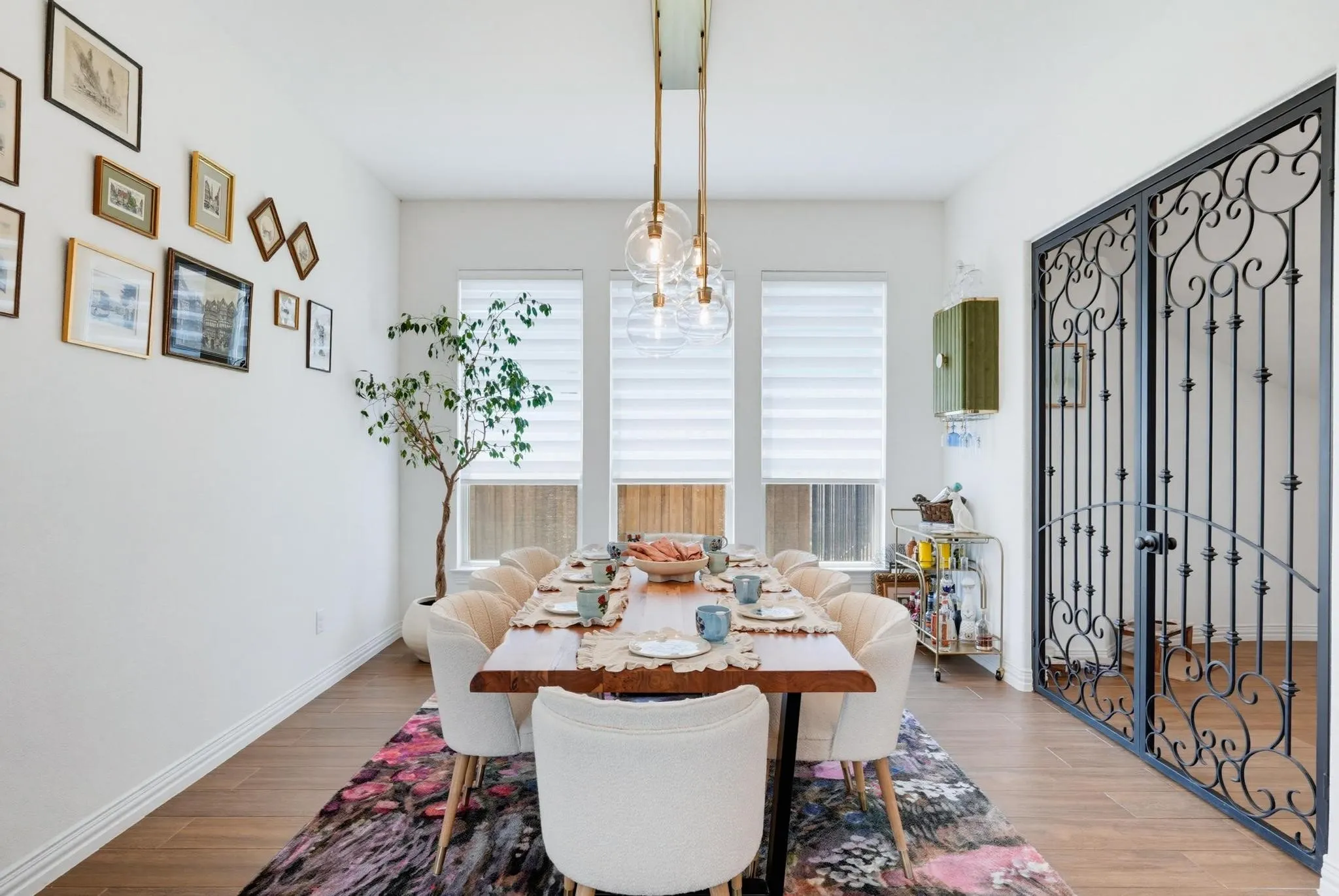Dining area featuring wood-finish flooring, white baseboards, and a modern linear chandelier with glass globes