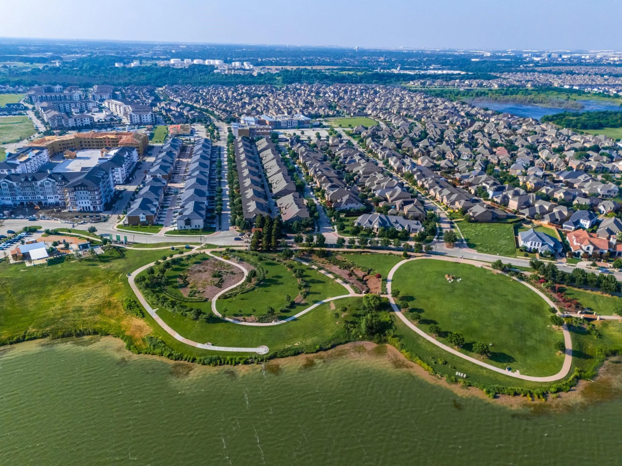 Expansive green spaces featuring walking paths, mature foliage, and waterfront access