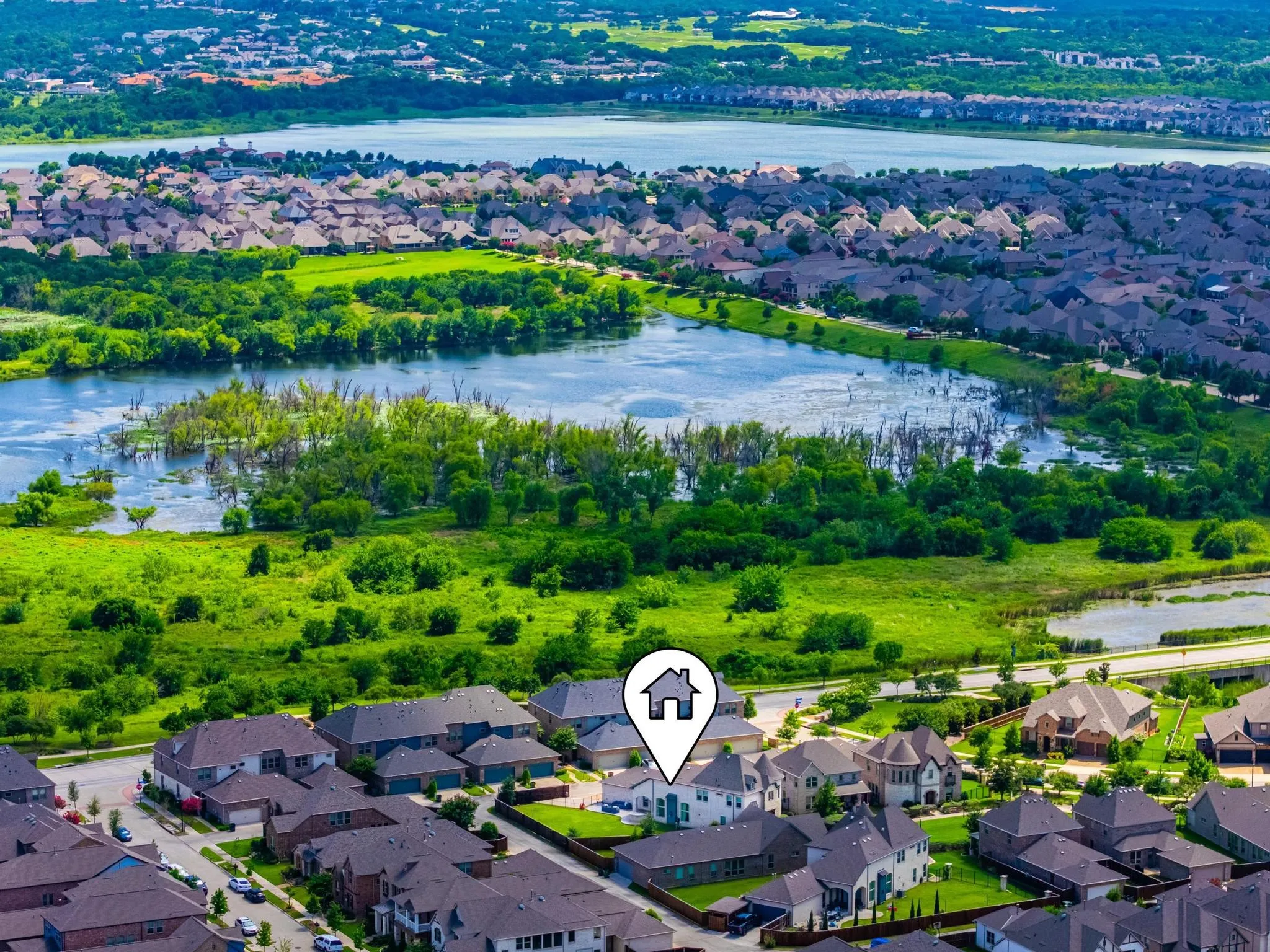 Aerial perspective of a residential neighborhood with varied architectural styles, featuring properties with dark-toned roofs and mature landscaping