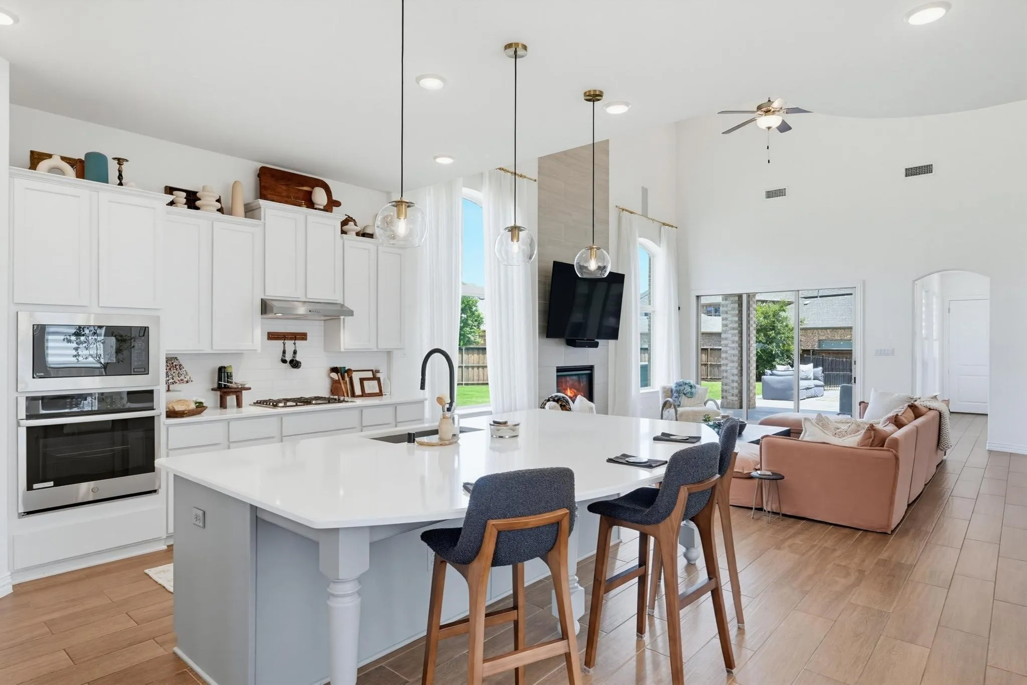 Bright open-concept kitchen and living area featuring a large center island with seating, stainless steel appliances, and wood-finish flooring