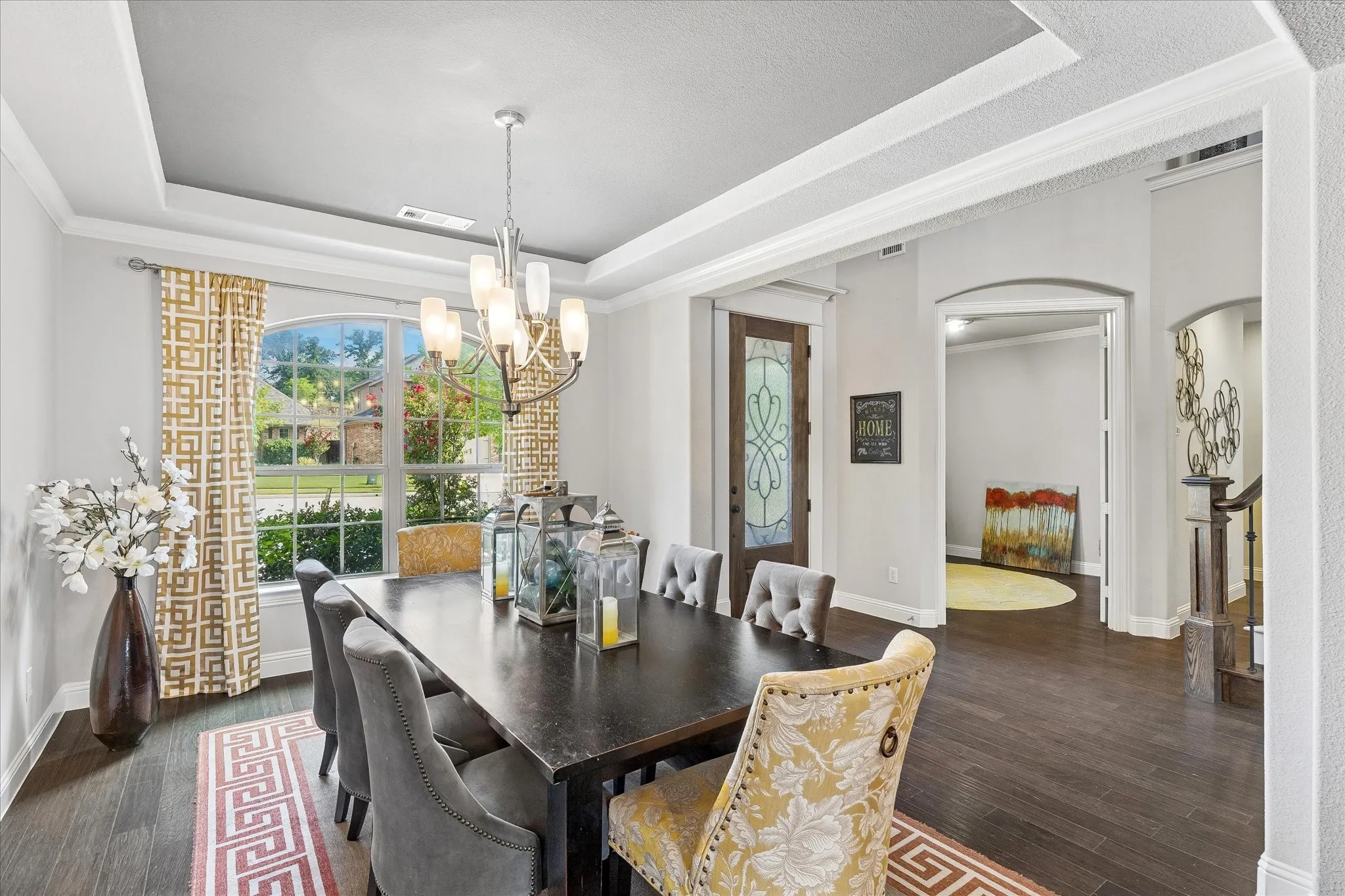 Dining area featuring a tray ceiling, arched entryway, and dark wood-finish flooring