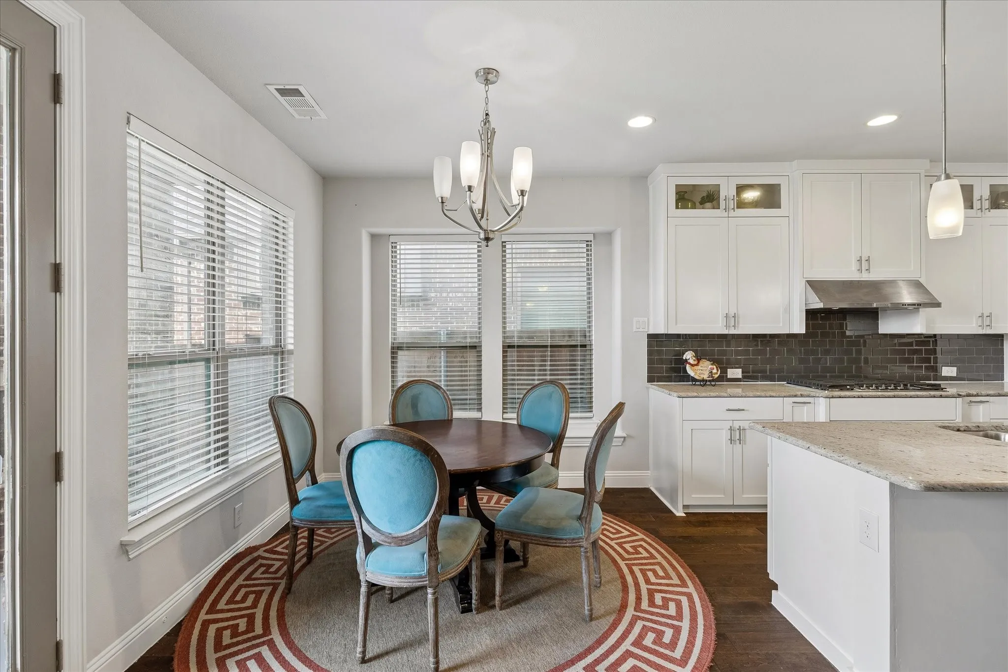 Kitchen and breakfast area featuring white cabinetry, a dark subway tile backsplash, and light-toned countertops