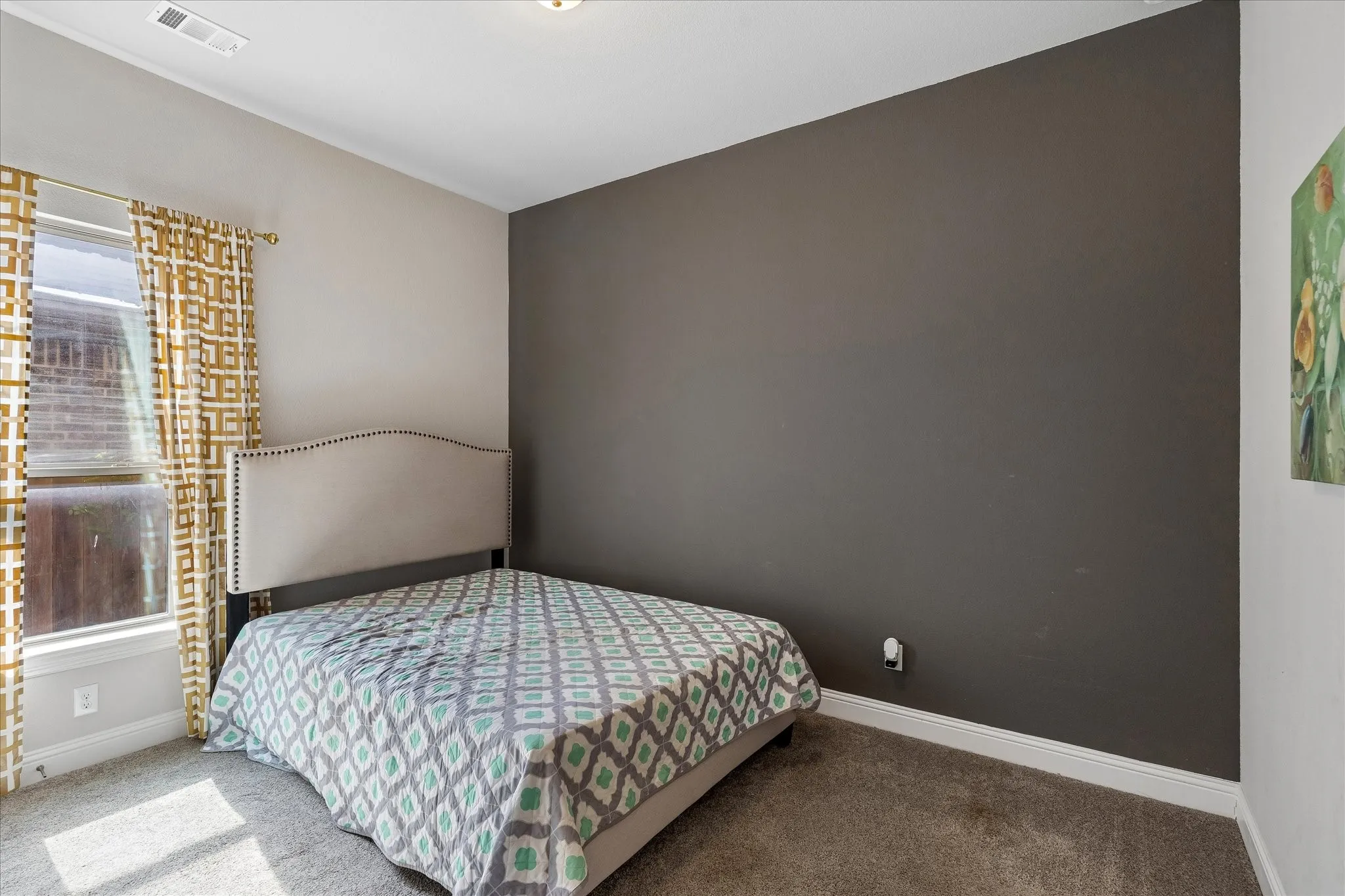 Room featuring a neutral grey carpet, a single window, white trim, and a contrasting accent wall