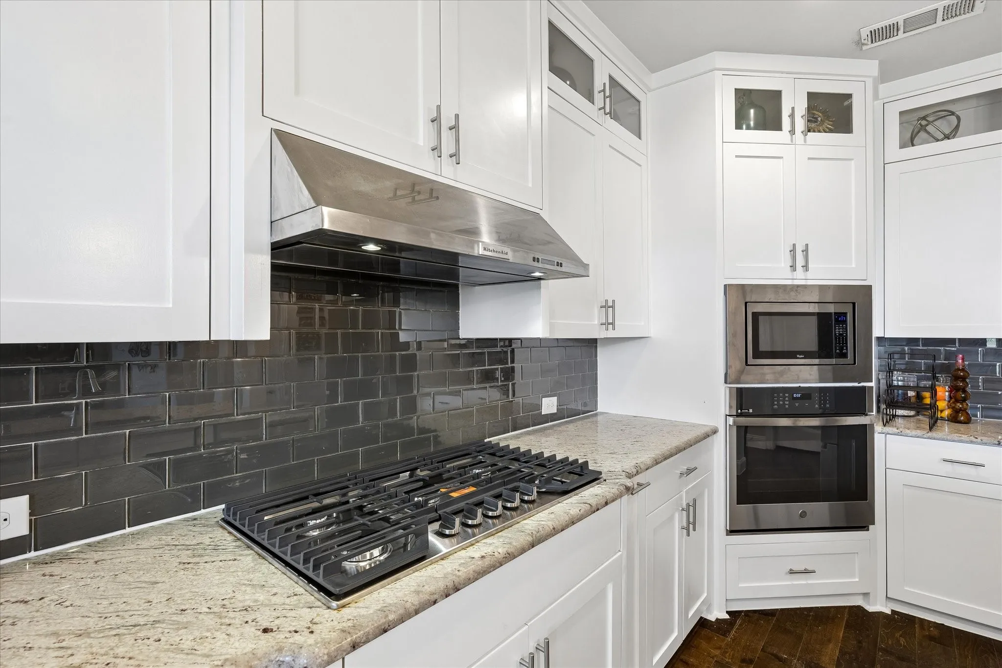 Kitchen featuring white shaker cabinetry, stainless steel range hood, built-in microwave and oven, gas cooktop, and granite countertops