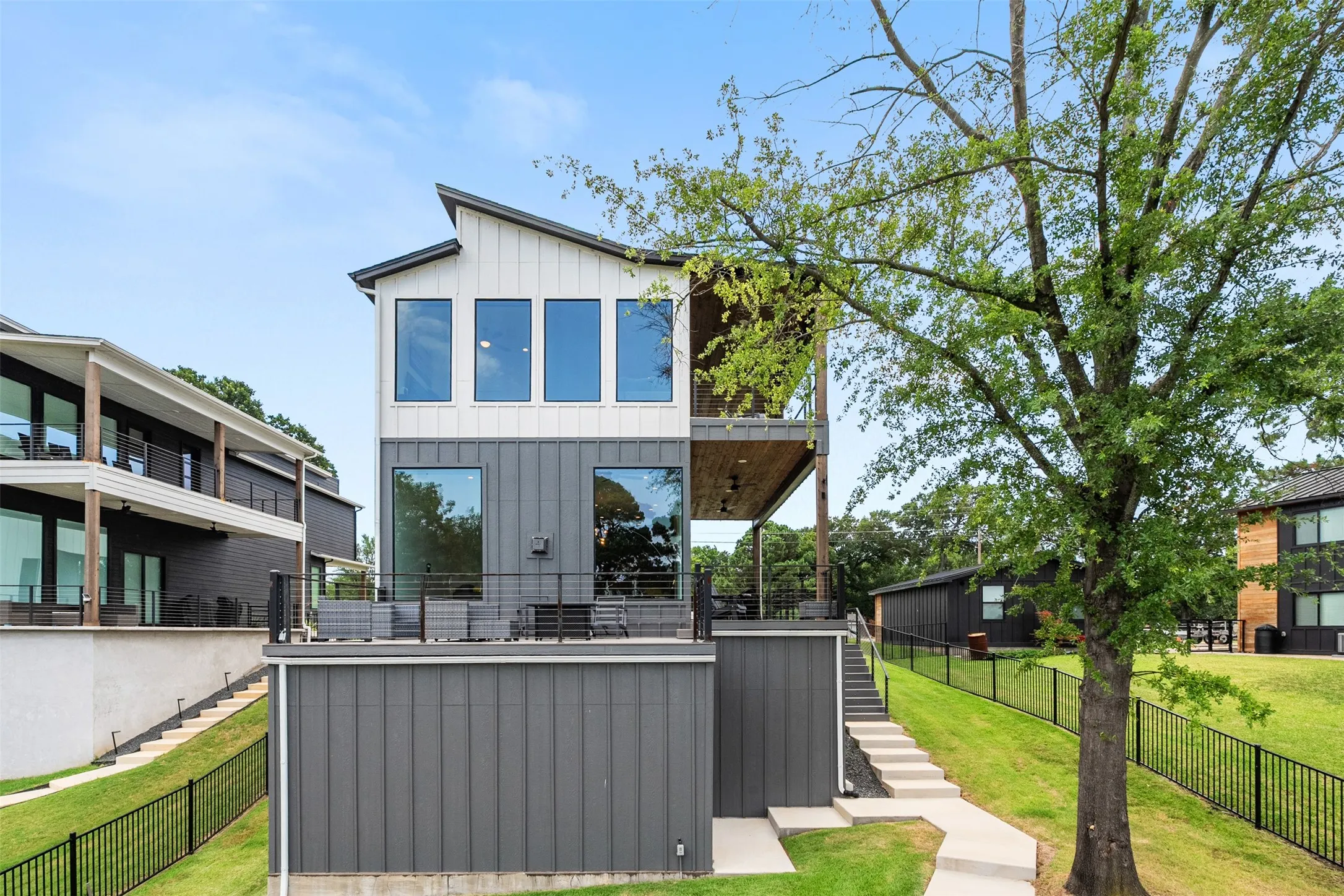 Modern two-story residence featuring a distinctive sloped roofline, vertical white siding, and dark gray paneling