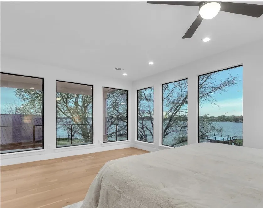 Floor-to-ceiling windows with black framing, wood-finish flooring, recessed lighting, and a modern ceiling fan