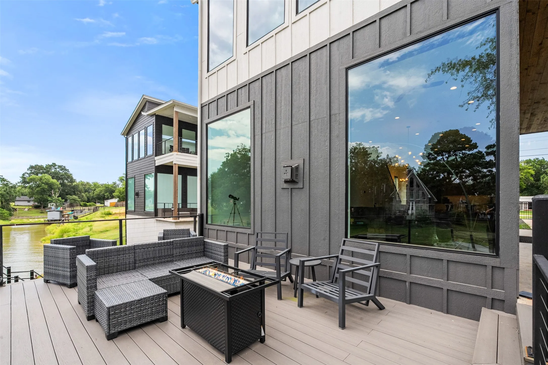 Spacious outdoor deck featuring composite decking, a clear glass railing, and a modern board-and-batten exterior