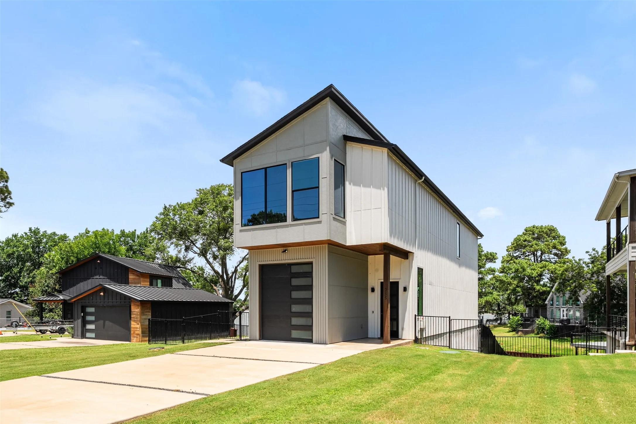 Contemporary exterior with light gray vertical siding, prominent second-story windows, and a dark garage door with horizontal glass inserts