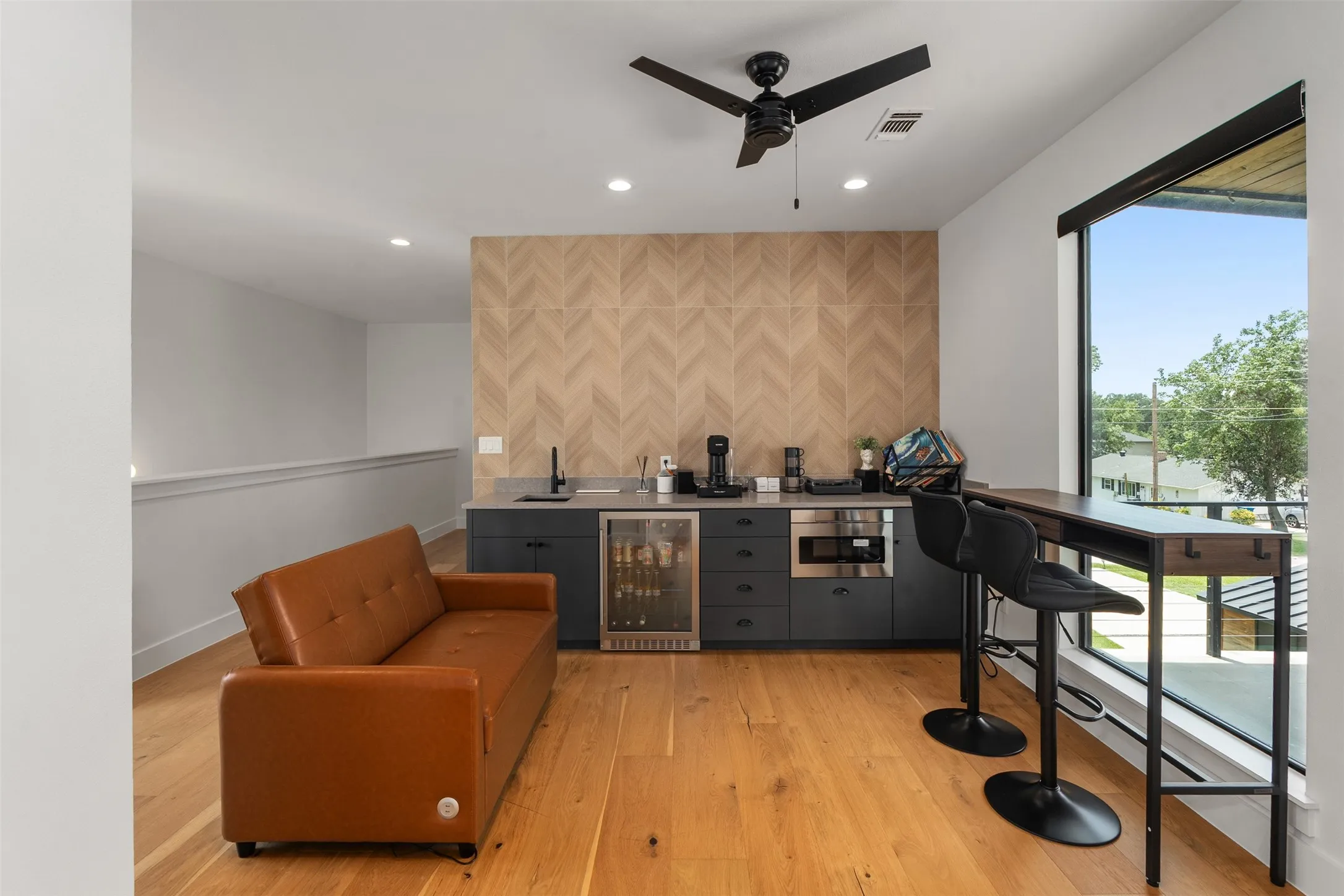 Contemporary wet bar featuring a beverage cooler, built-in microwave, and herringbone-patterned accent wall