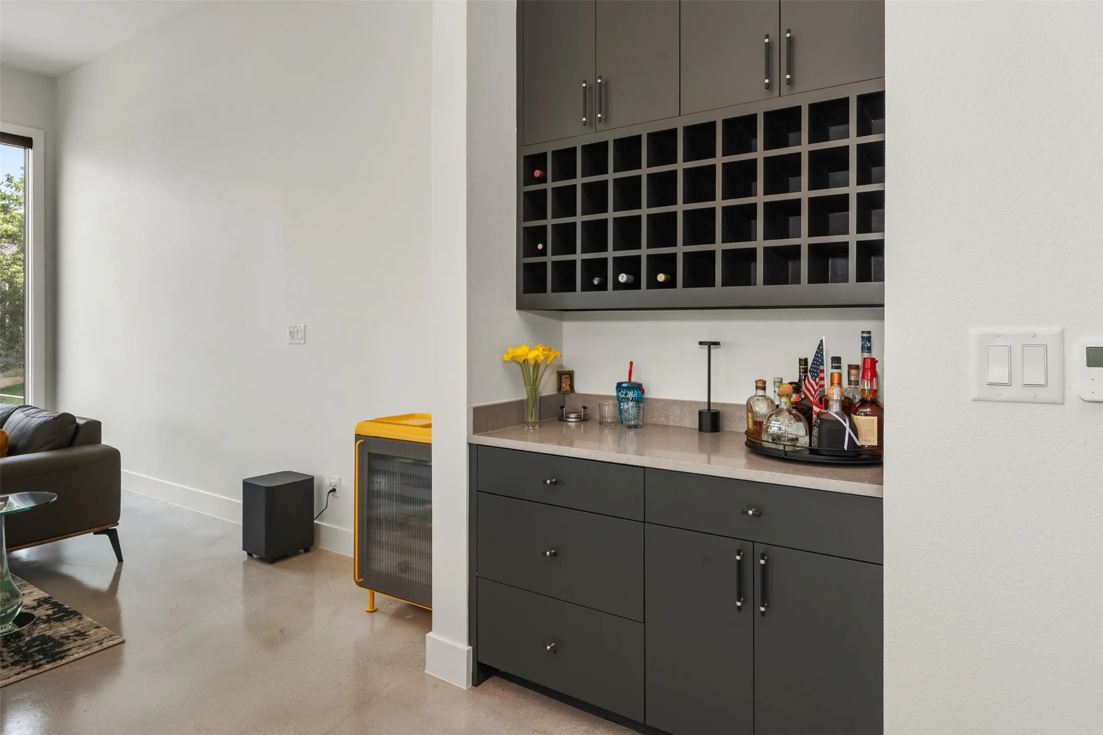 Built-in wet bar featuring dark gray cabinetry, integrated wine storage, and a light-toned countertop