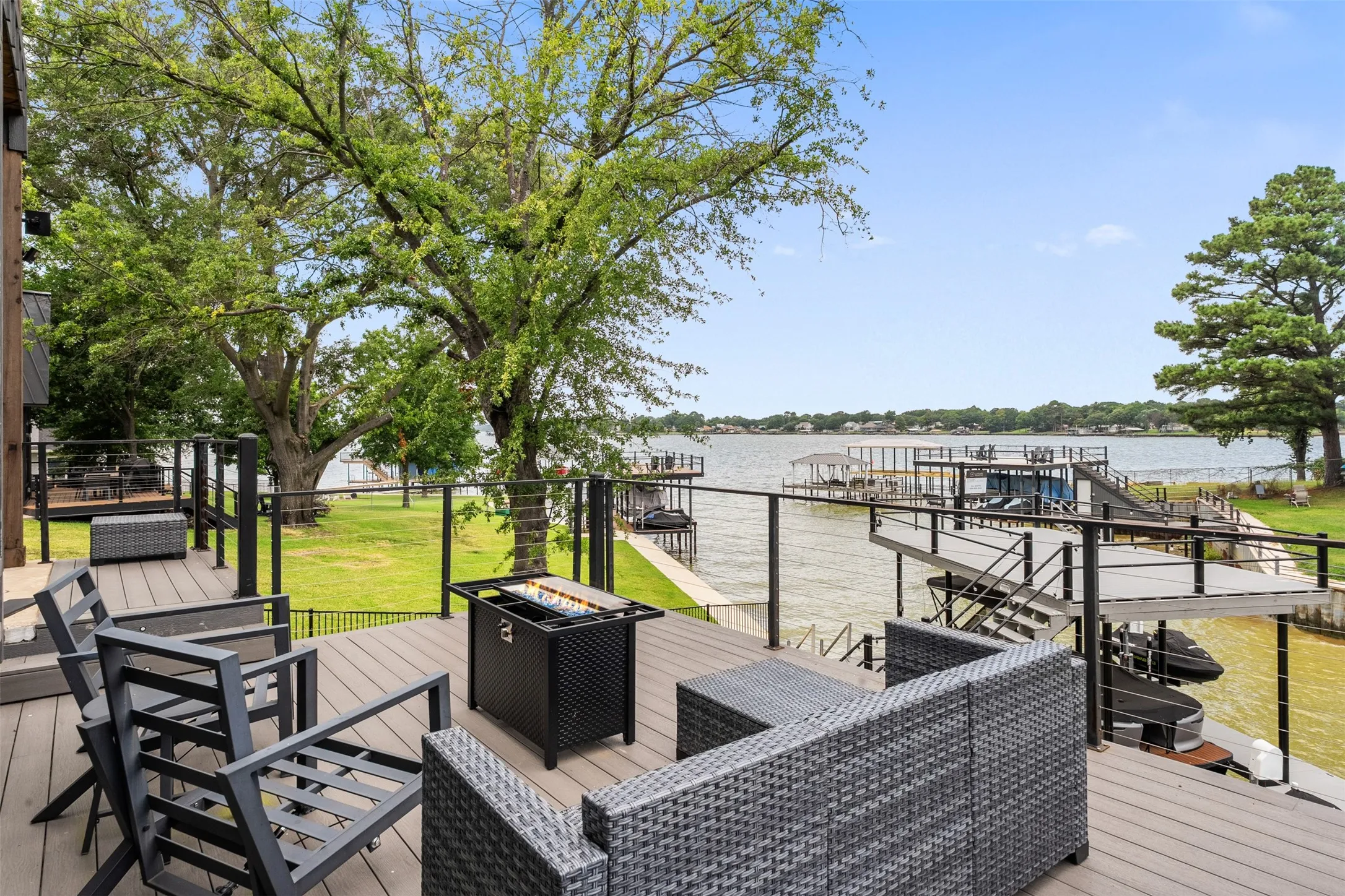 Spacious outdoor deck with composite decking, black metal railings, and clear panel inserts overlooking the water