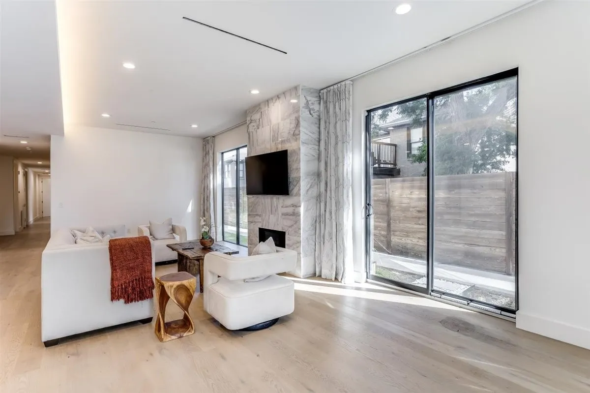 Spacious living area featuring light wood-finish flooring, a stone-clad fireplace surround, and large sliding glass doors