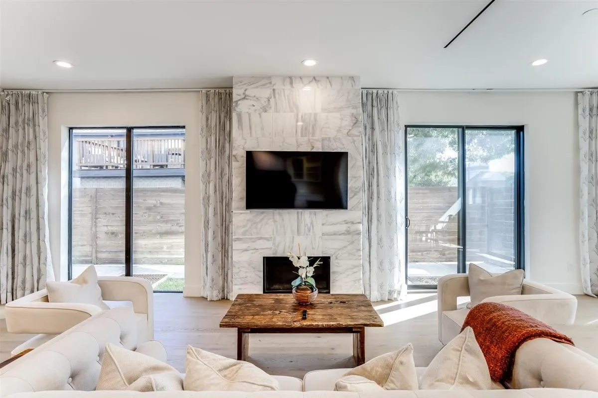 Living area featuring a marble-clad fireplace, integrated media display, recessed lighting, and wood-finish flooring