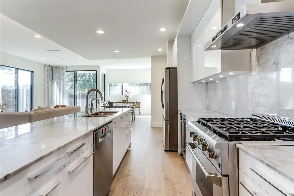 Gourmet kitchen featuring a gas range, stainless steel appliances, white cabinetry, and light-toned wood-finish flooring