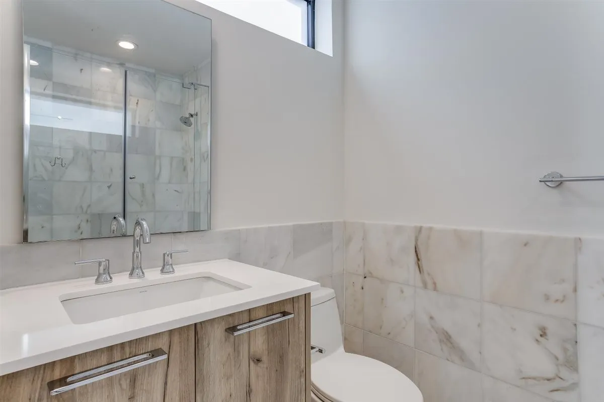 Bathroom featuring a wood-finish vanity with a white countertop and integrated sink, chrome fixtures, and a wall-mounted mirror