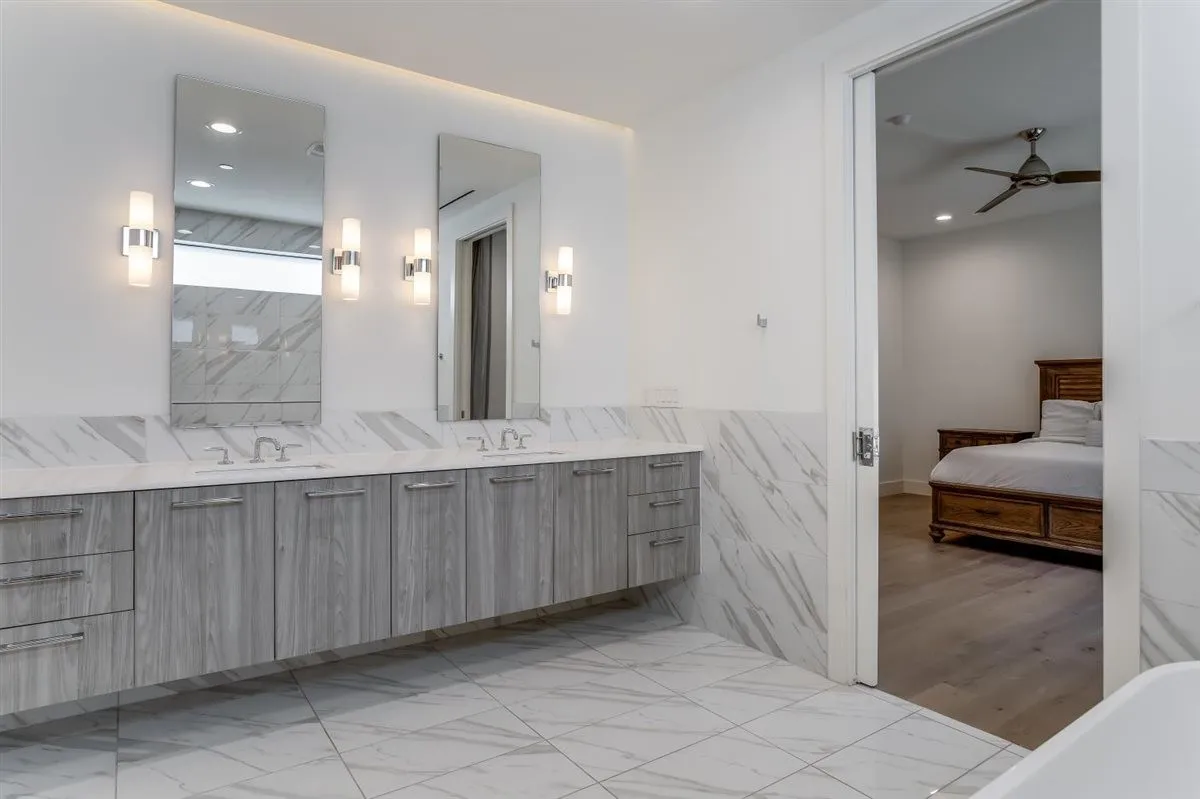 Bathroom featuring a dual vanity with grey wood-finish cabinetry and chrome hardware, undermount sinks, and white countertops