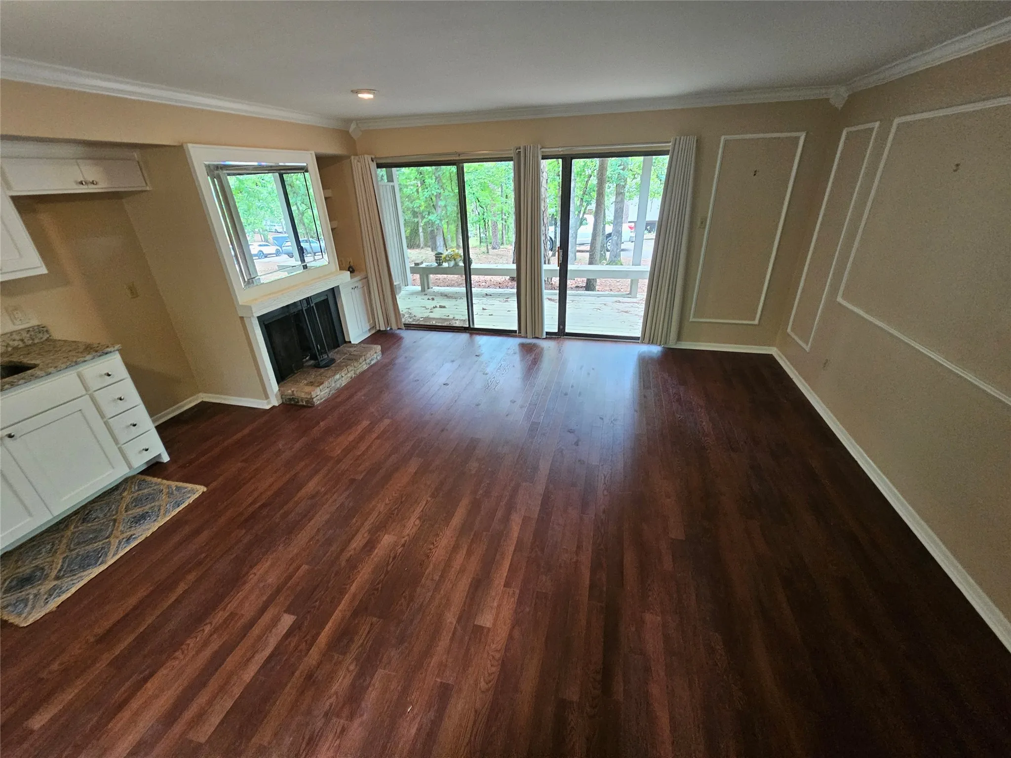 Spacious living area featuring wood-finish flooring, a brick fireplace with hearth, and large sliding glass doors providing access to the exterior