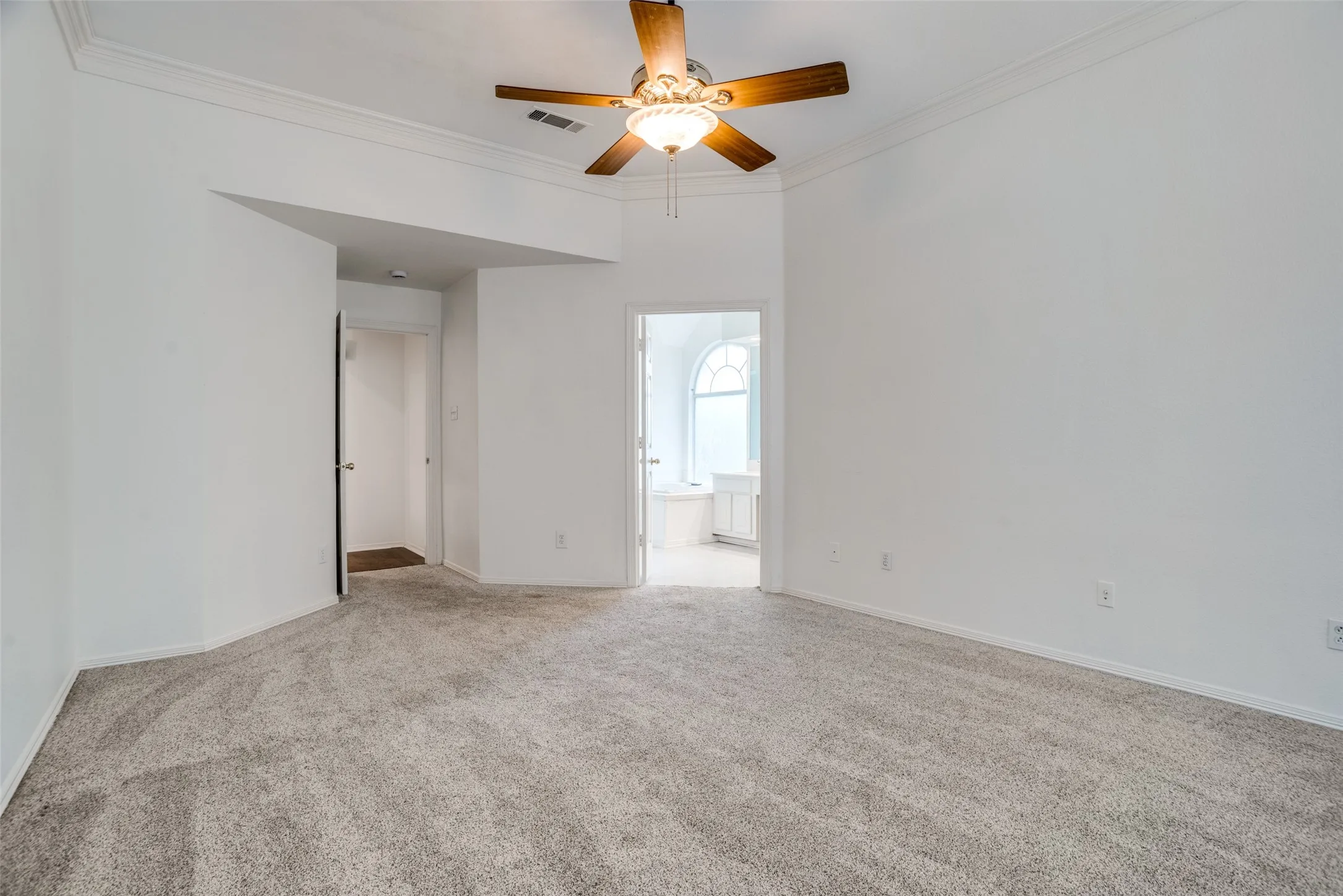 Spare room featuring ornamental molding, light carpet, and a ceiling fan