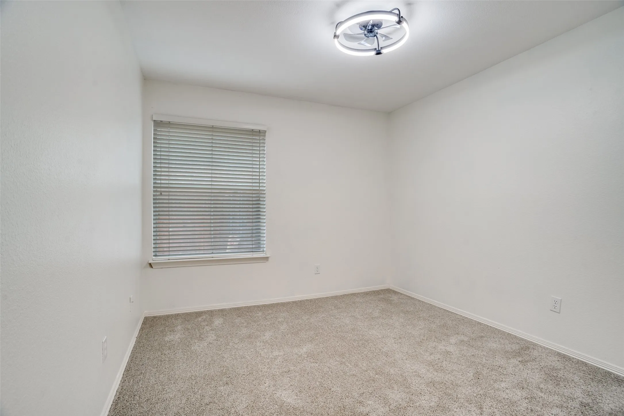 Carpeted spare room featuring baseboards