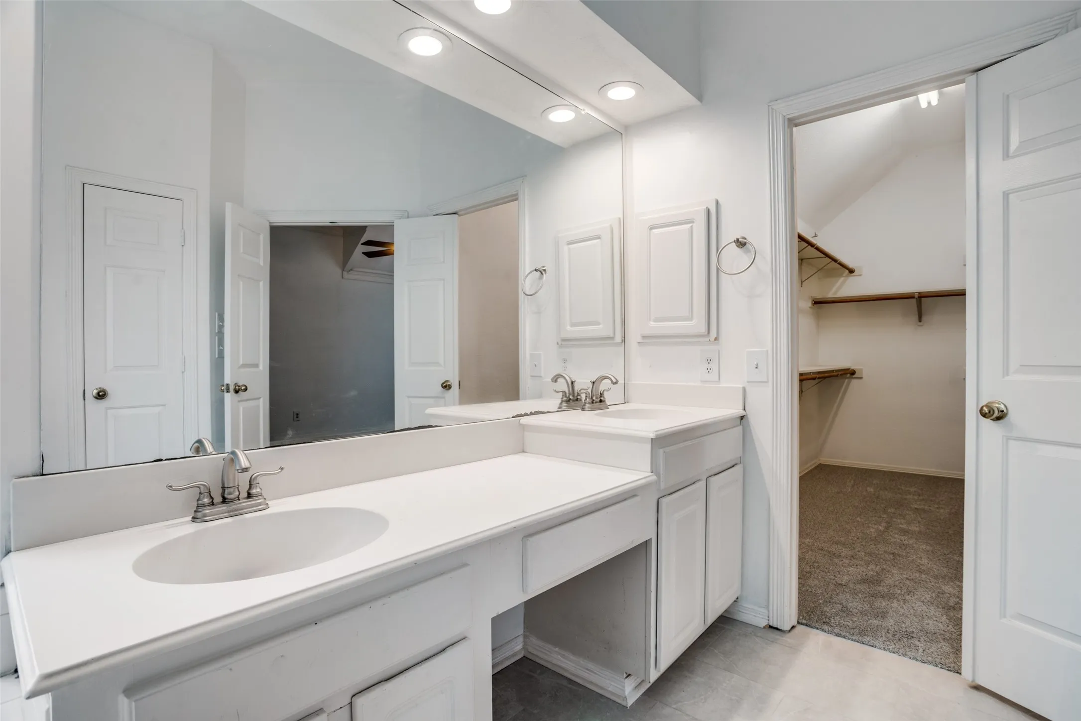 Bathroom featuring double vanity, a spacious closet, light carpet, and recessed lighting