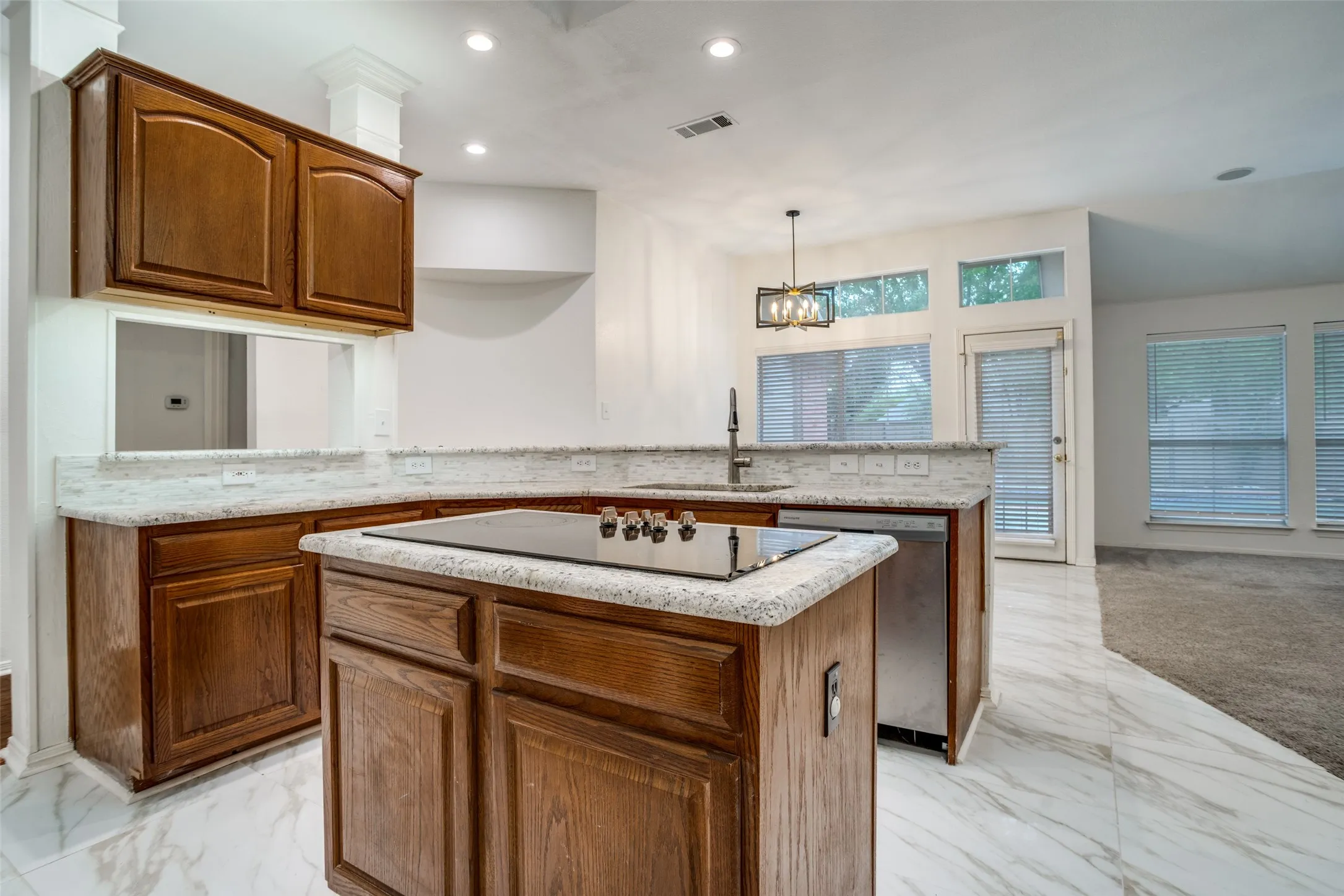 Kitchen with a peninsula, wood finish cabinets, dishwasher, and light marble finish flooring