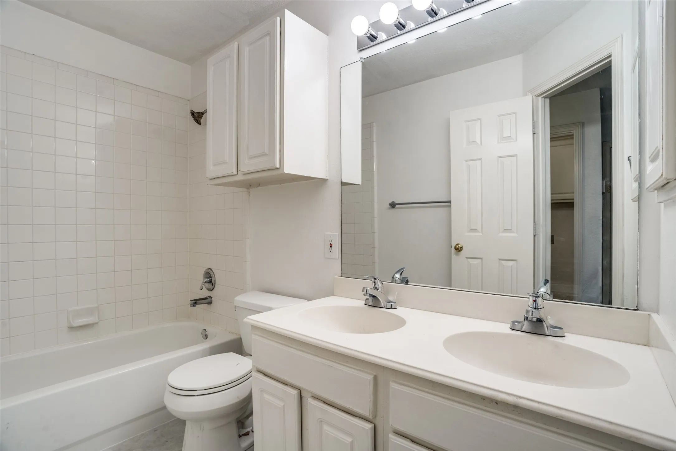 Bathroom with double vanity and shower / washtub combination