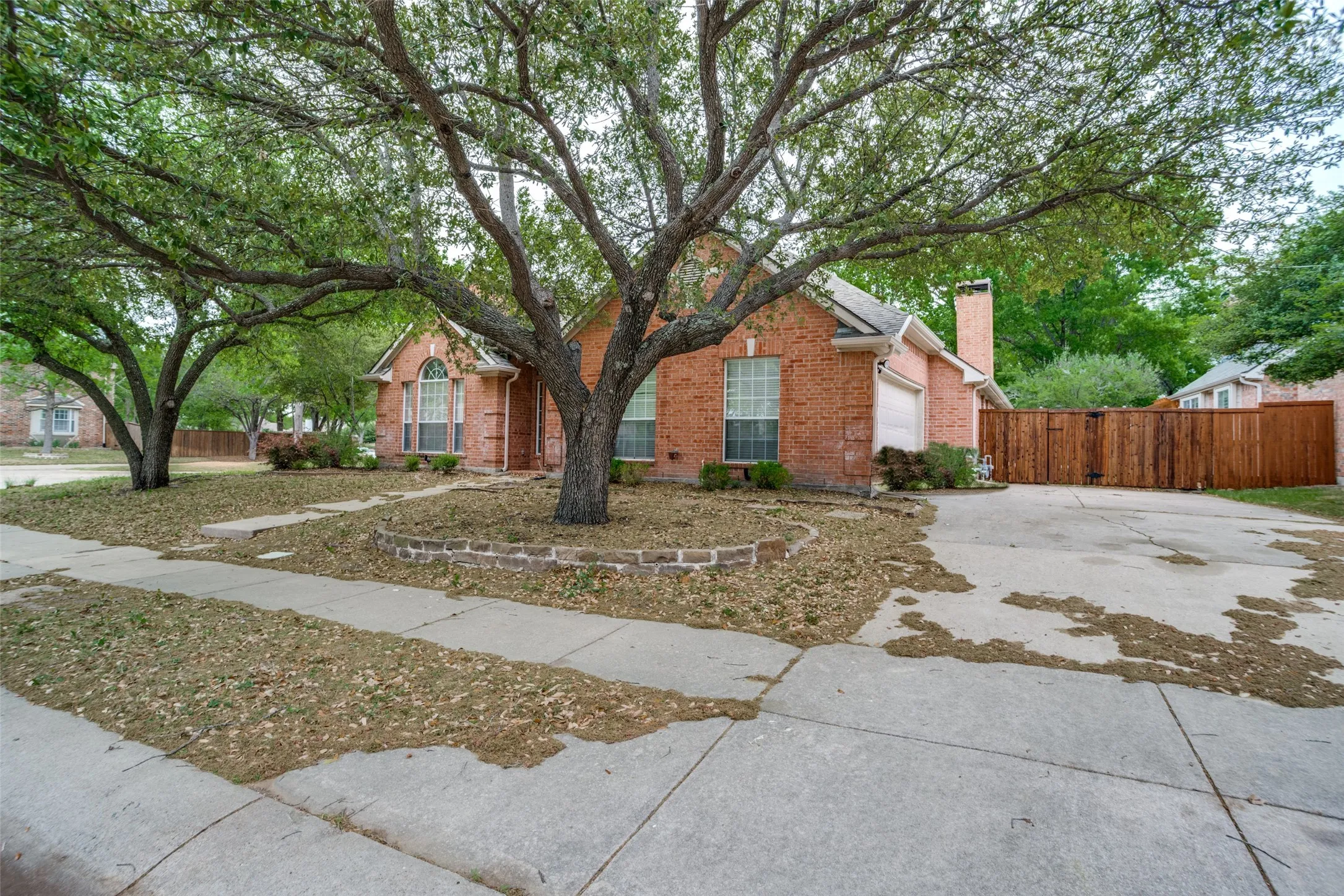 View of front of property featuring brick siding, a chimney, concrete driveway, and a garage