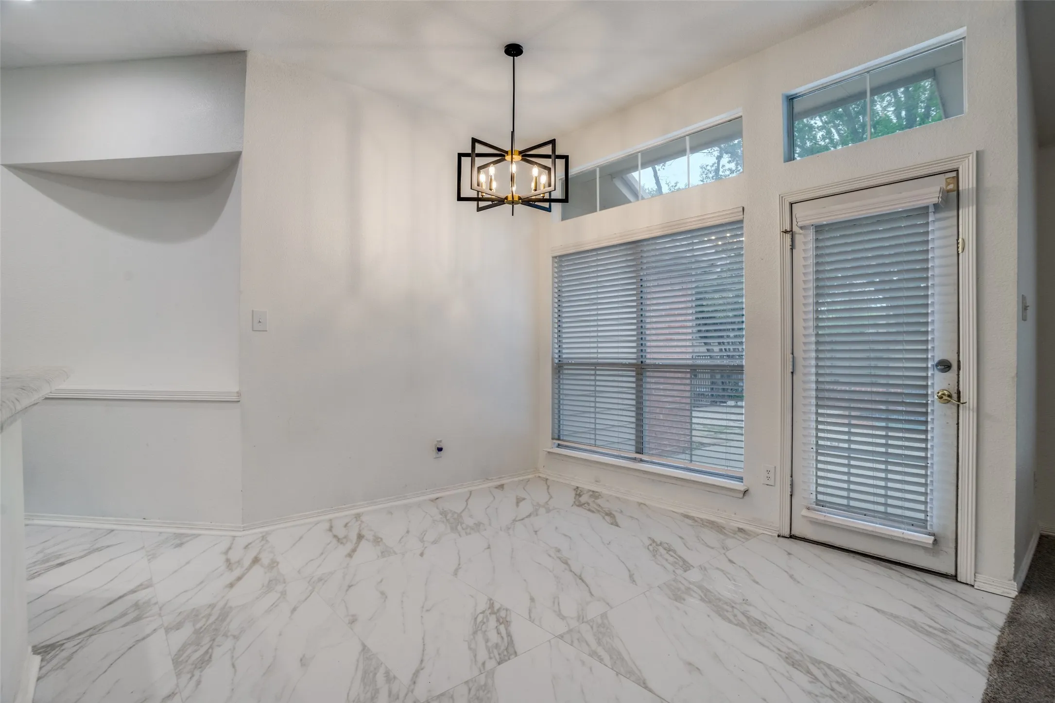 Unfurnished dining area featuring a chandelier and light marble finish flooring