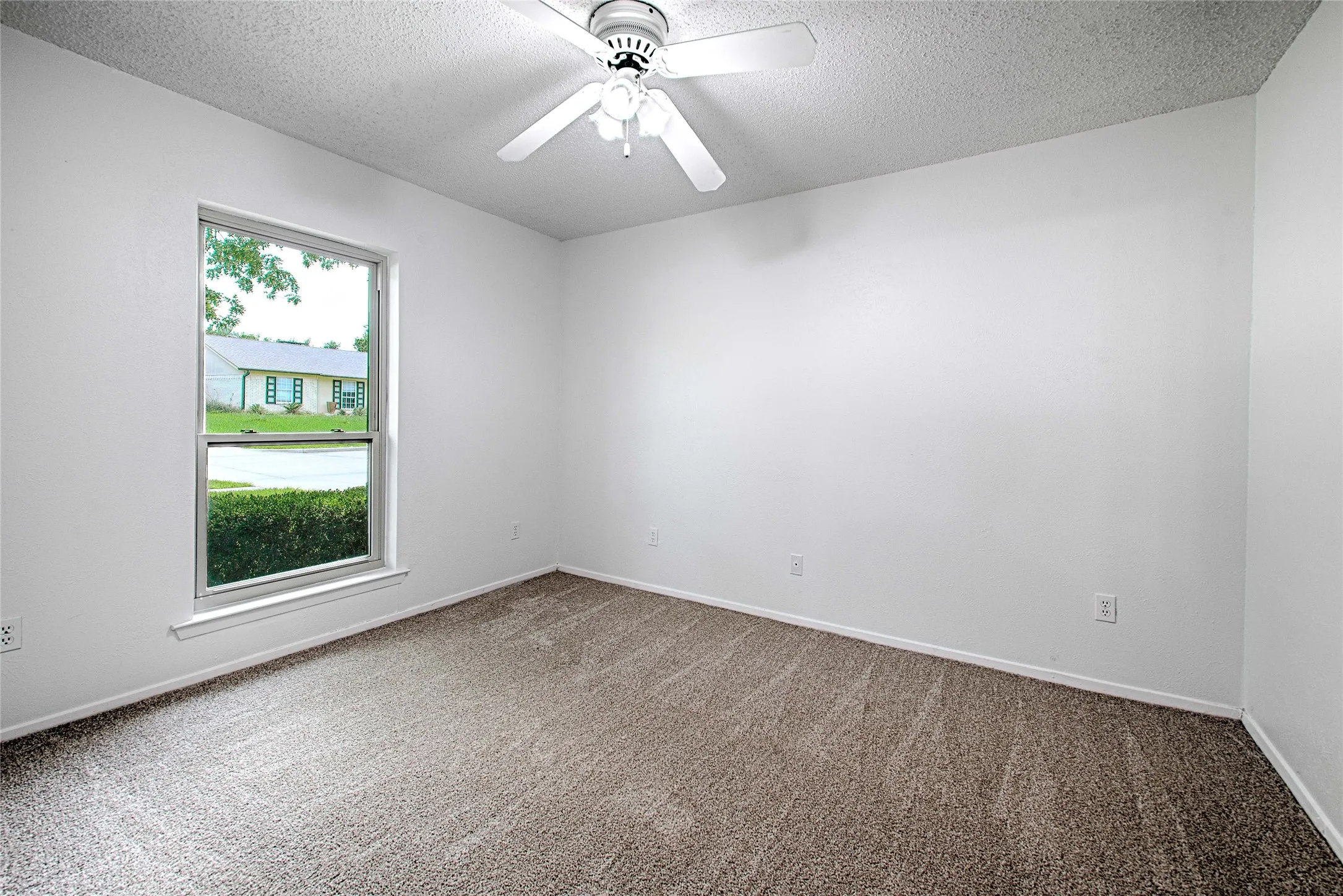 Neutral tone interior featuring white walls, textured ceiling, and brown carpet flooring