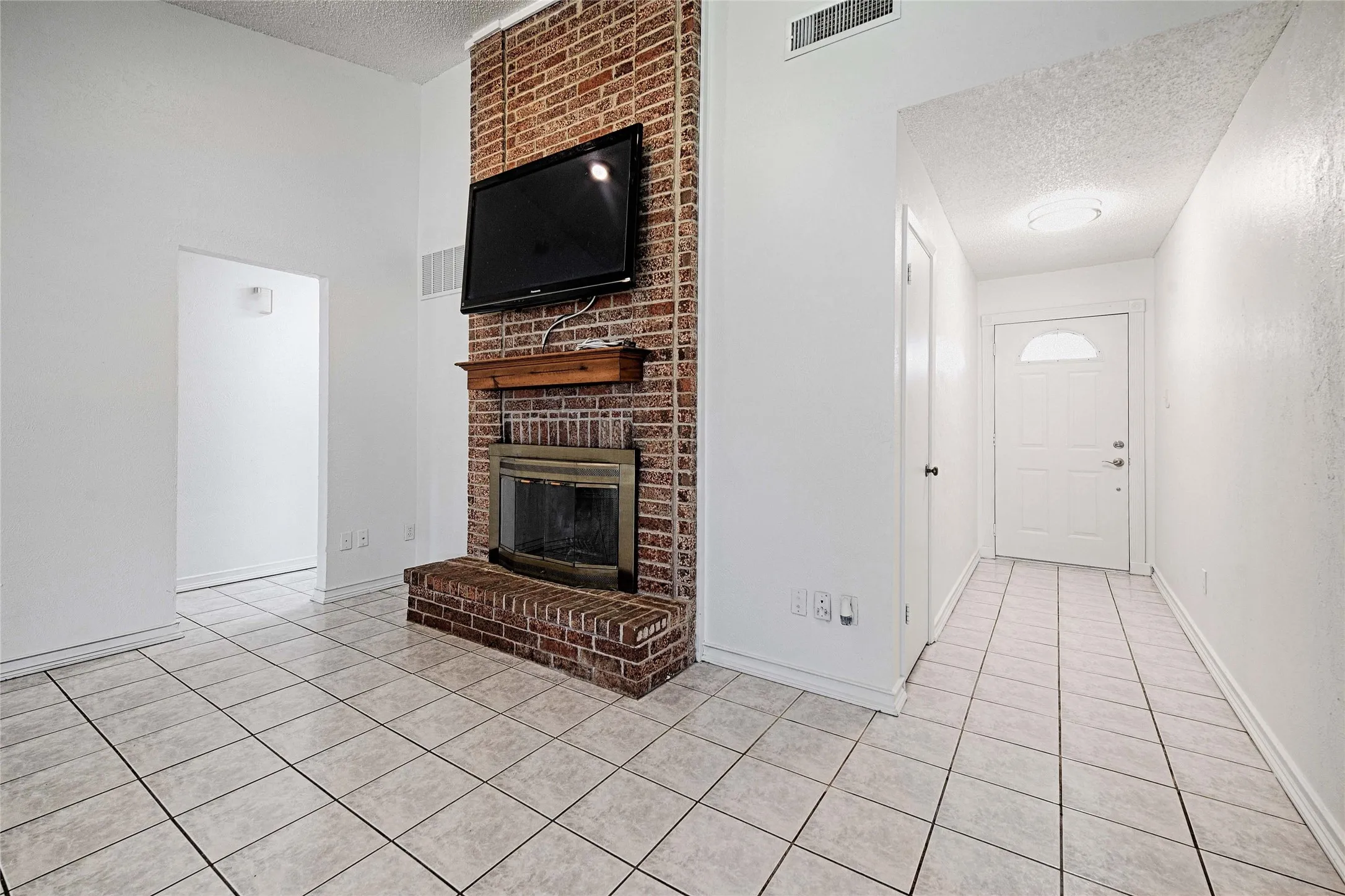 Living area featuring a brick fireplace with a wood mantle, a ceiling fan, and tile flooring