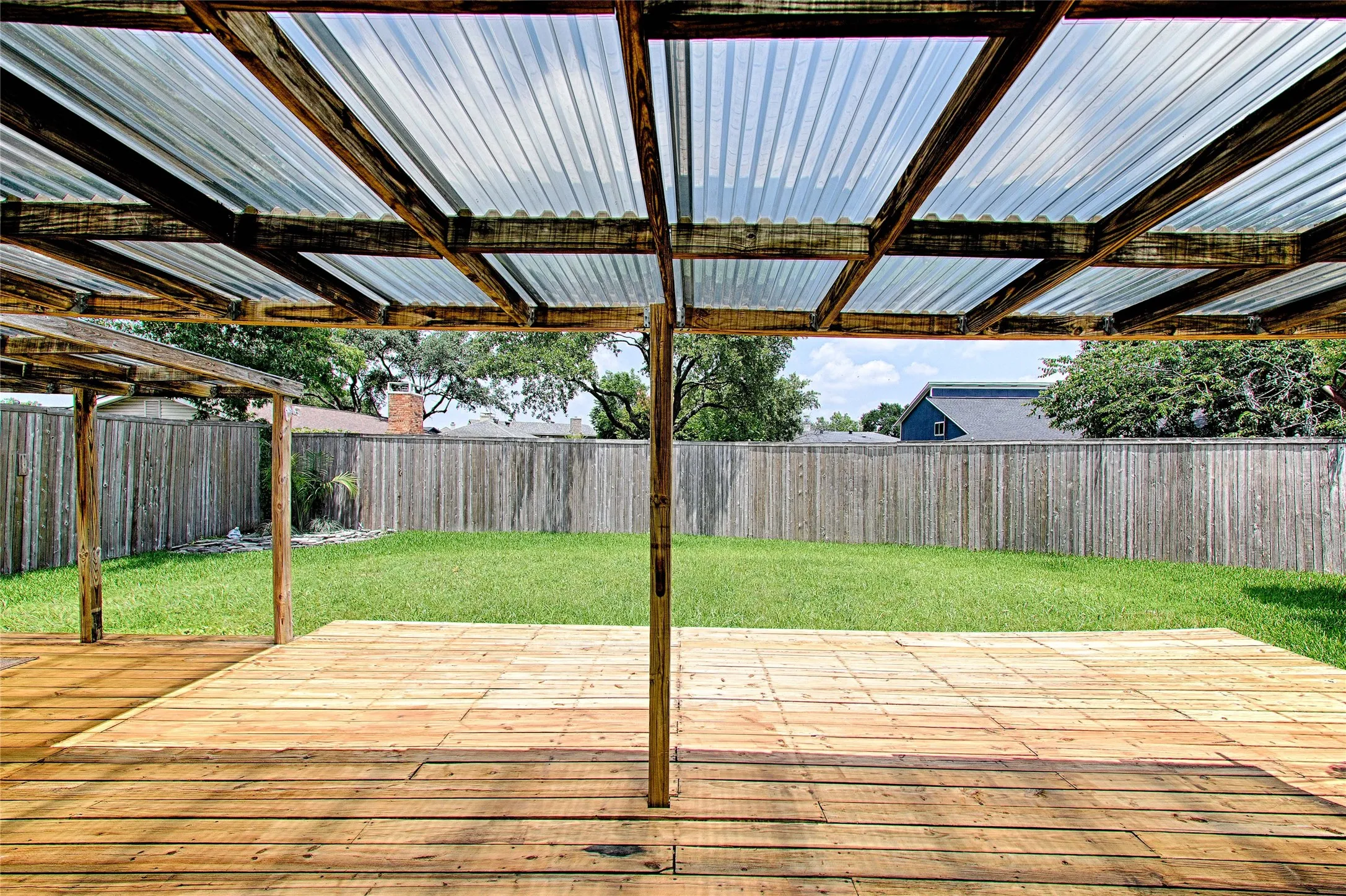 Spacious outdoor patio with wood-finish decking and a translucent corrugated roof