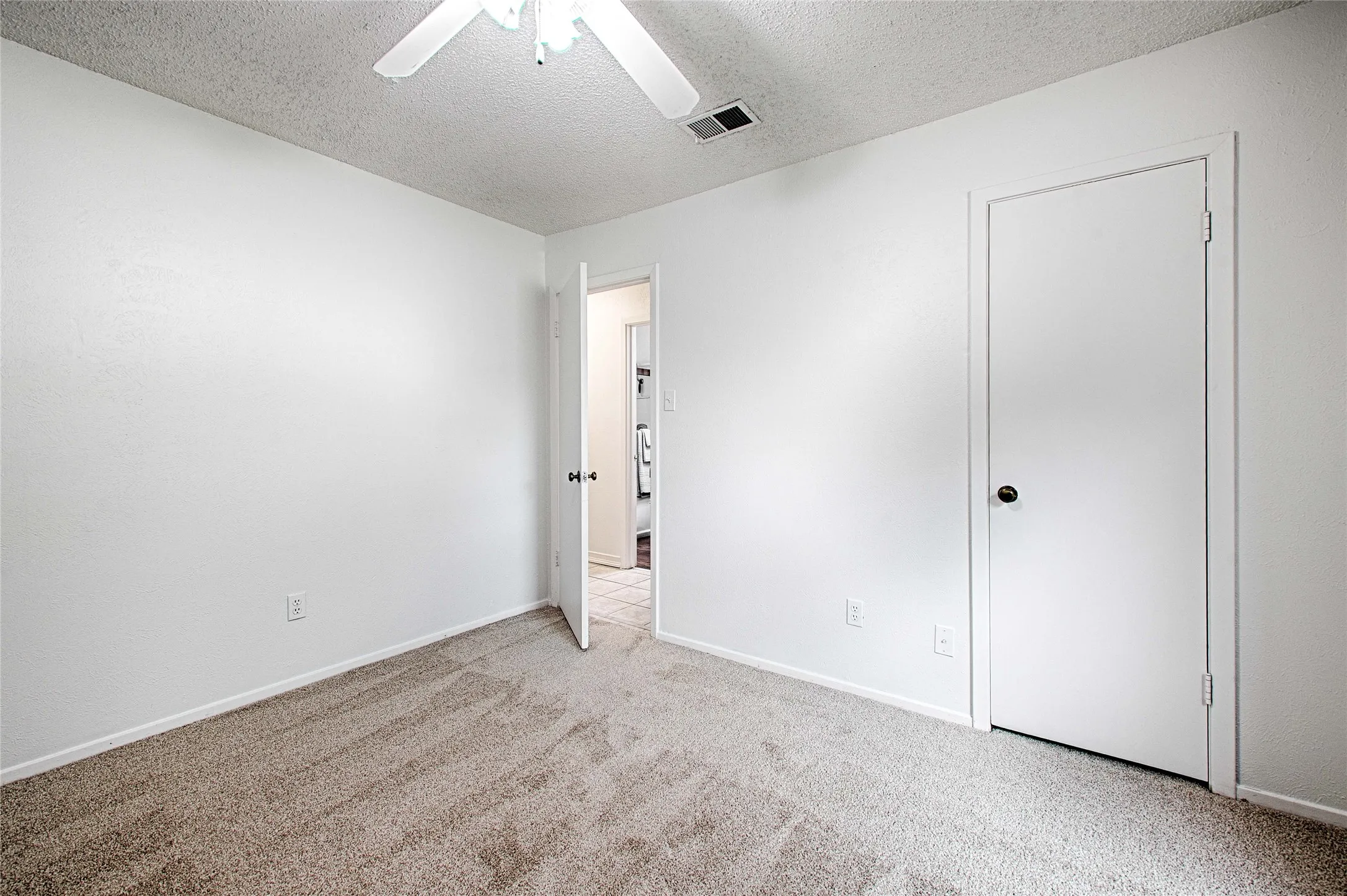 Carpeted room with white walls, a ceiling fan, and white trim