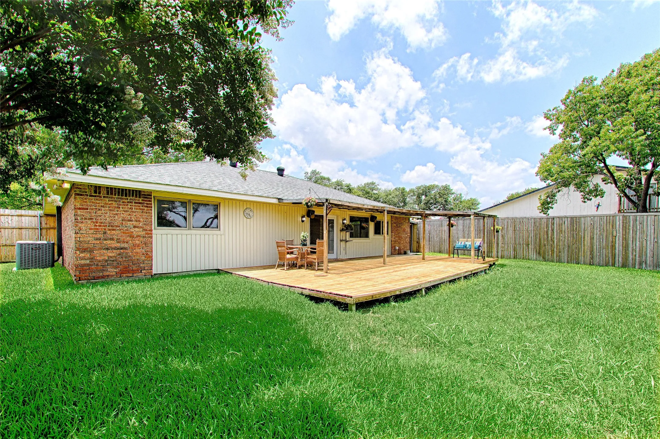 Expansive backyard featuring a lush lawn, privacy fencing, and mature trees