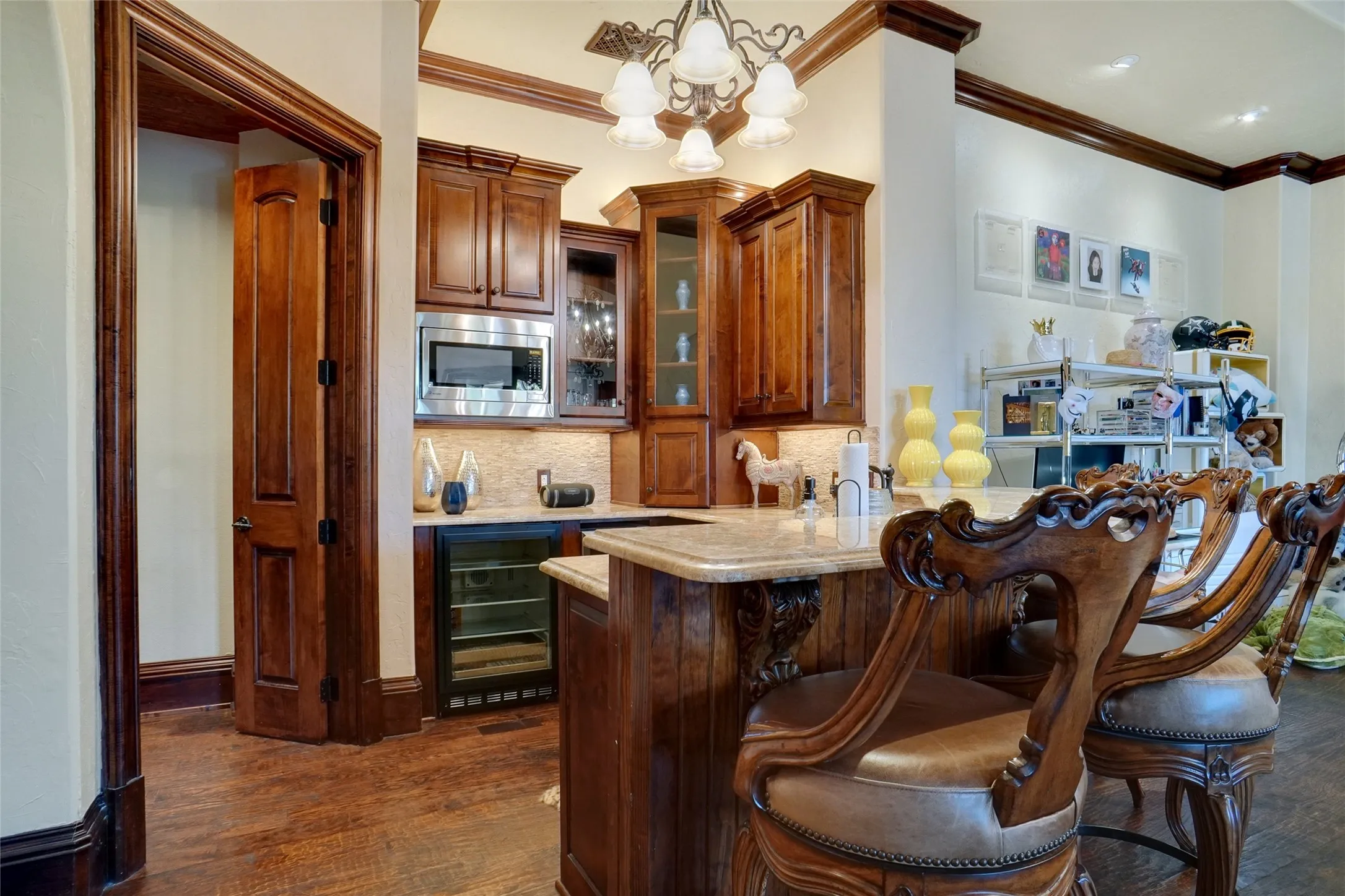 Elegant wet bar area showcasing custom stained cabinetry, a built-in microwave, integrated beverage refrigerator, and a functional kitchenette setup.