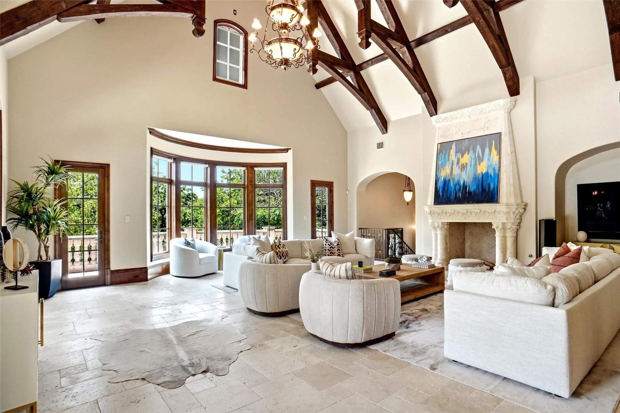 Another view of the Great Room in the extended secondary house. Spacious living area featuring a vaulted ceiling with exposed wood beams, a stone fireplace, large bay windows, and light-toned tile flooring