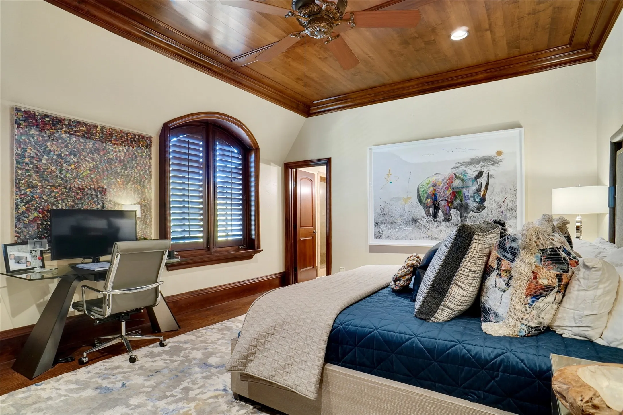 Spacious guest bedroom on the second level featuring elegant crown molding, recessed lighting, and a warm wood-paneled ceiling with an integrated ceiling fan.