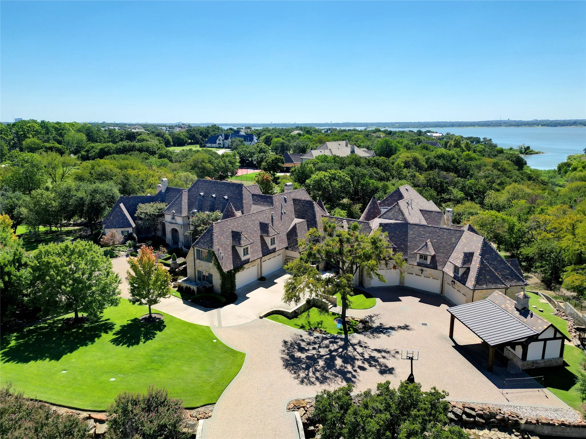 Expansive property featuring a multi-gabled roofline, stone and stucco exterior, and multiple garage bays. Right side of the home is the secondary residence.