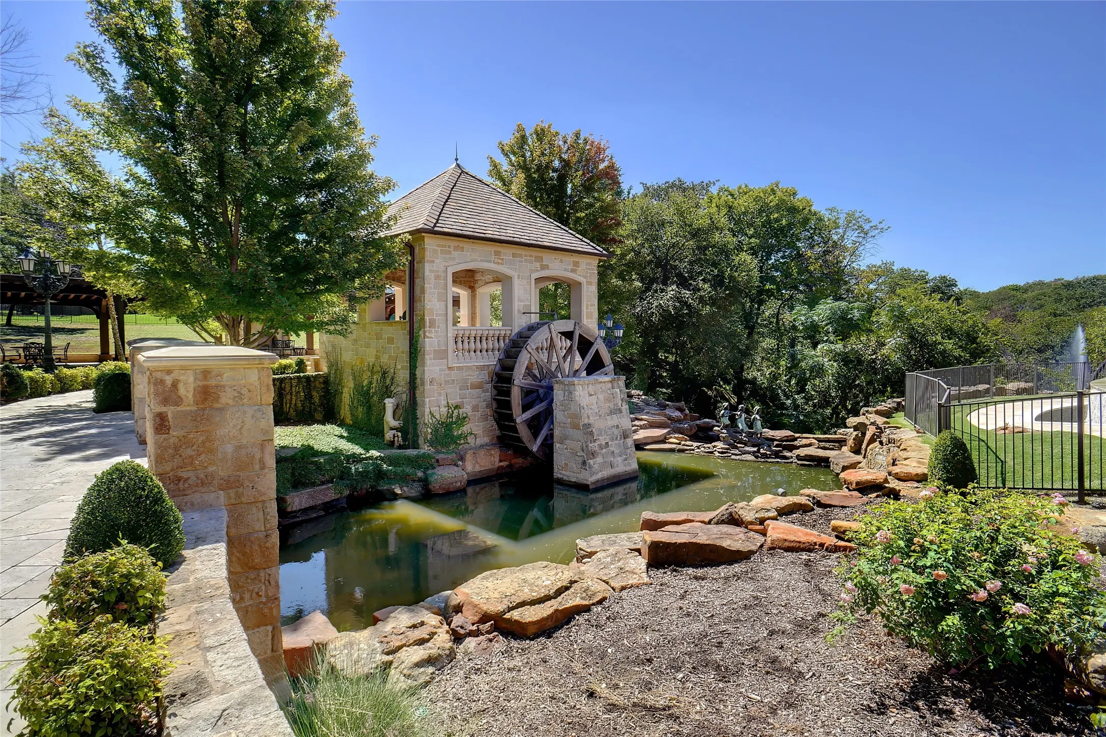 Charming water wheel feature nestled by the pond and gazebo.