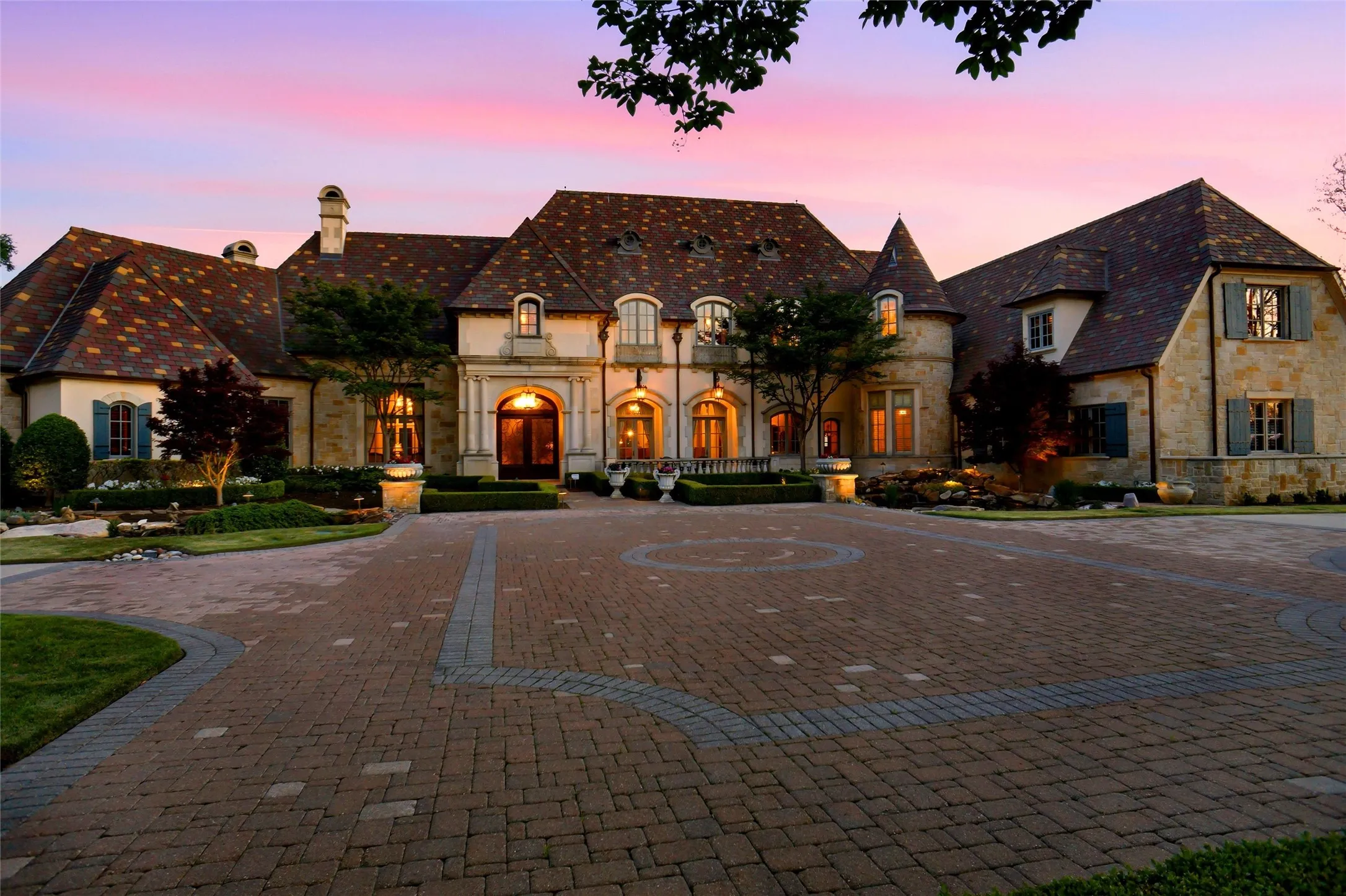 French Colonial architecture featuring a stone and stucco facade, multi-hued tile roof, and decorative window shutters