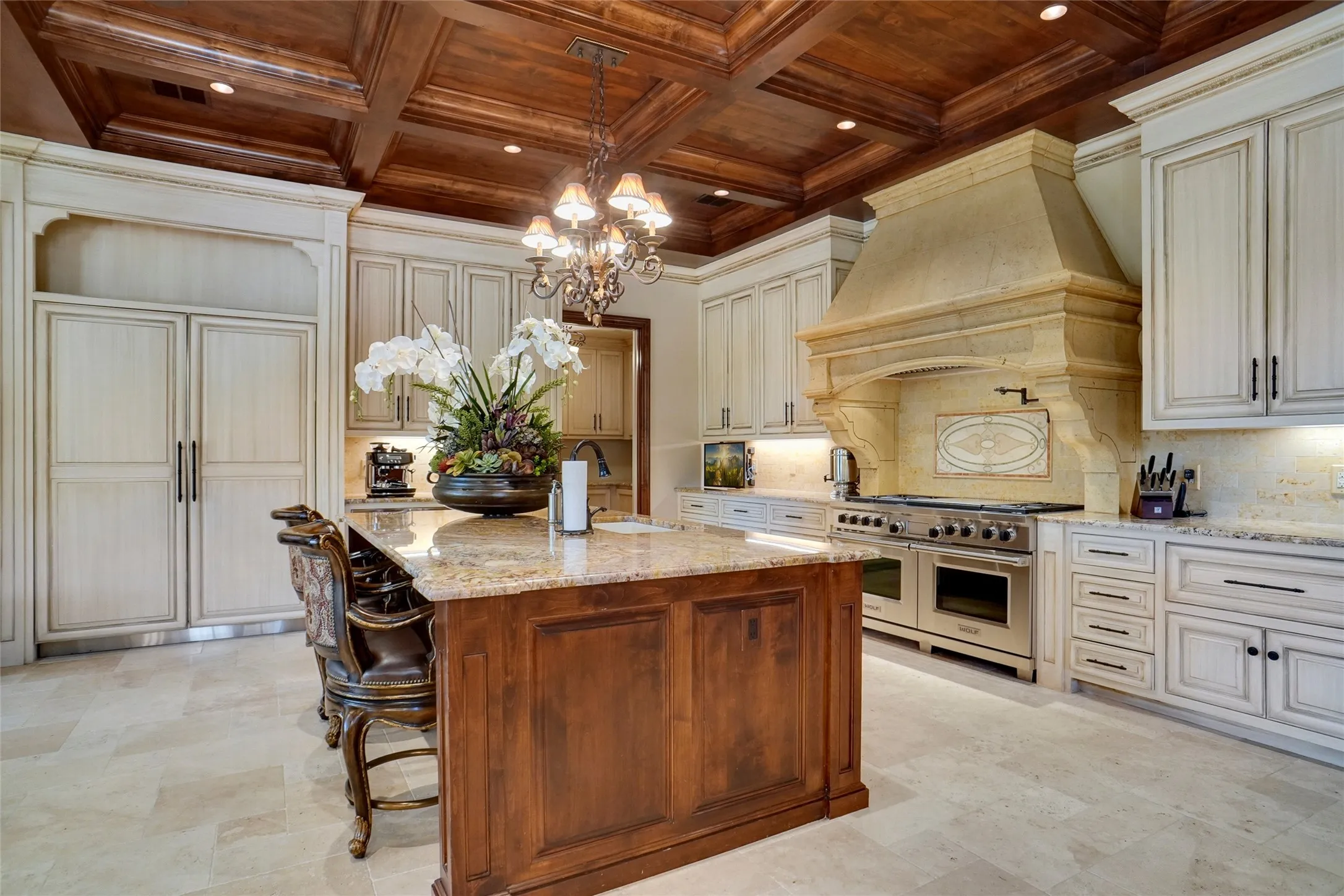 Gourmet kitchen featuring a wood-paneled coffered ceiling, a large central island with stone countertops, custom cabinetry, integrated refrigeration, and a professional-grade range with a stone-clad hood located in the SECOND residence.