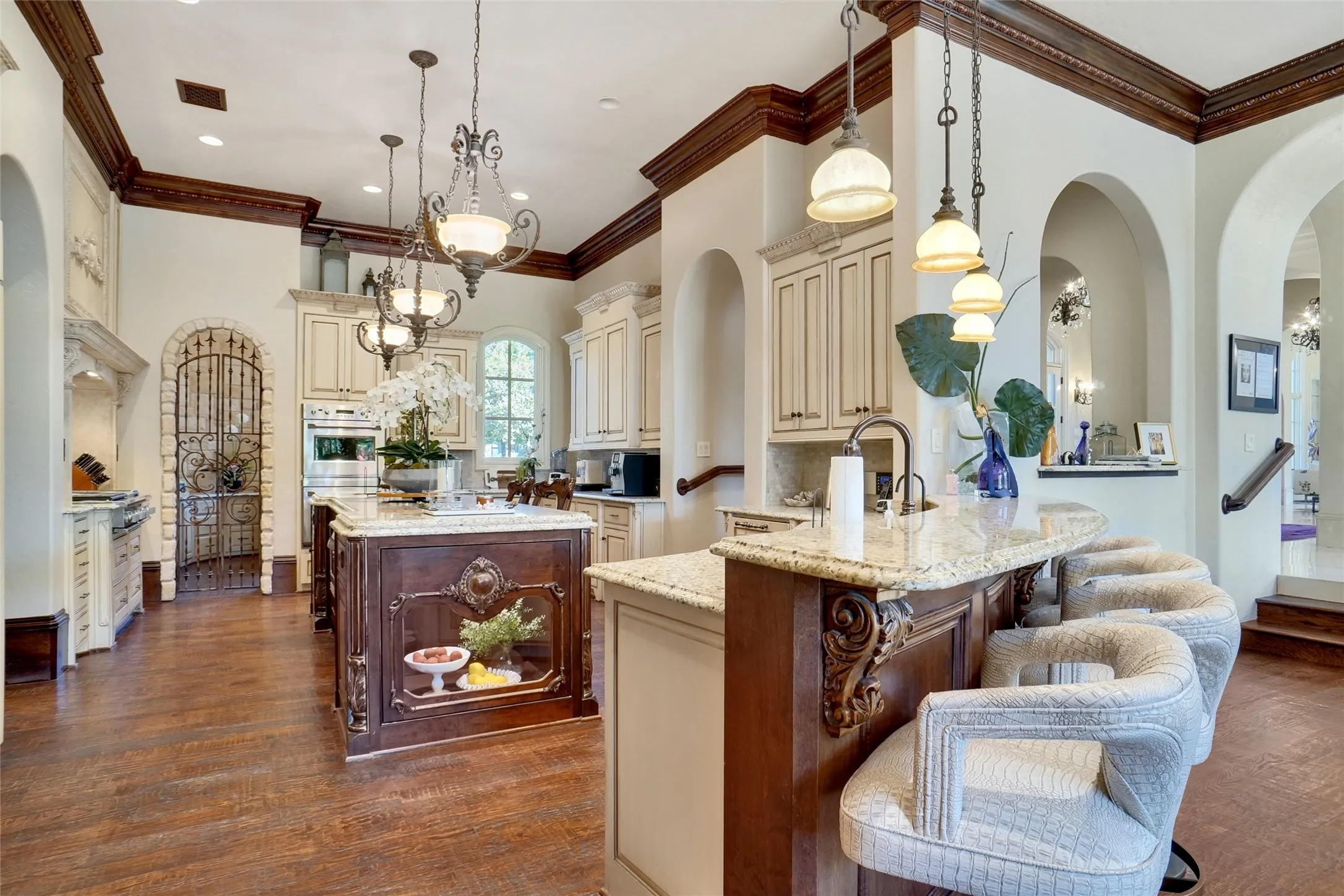 Gourmet kitchen featuring wood-finish flooring and expansive counter space with commercial grade appliances, granite countertops and a secondary office space through the kitchen. Off to the right is the dry bar or butler's pantry space.