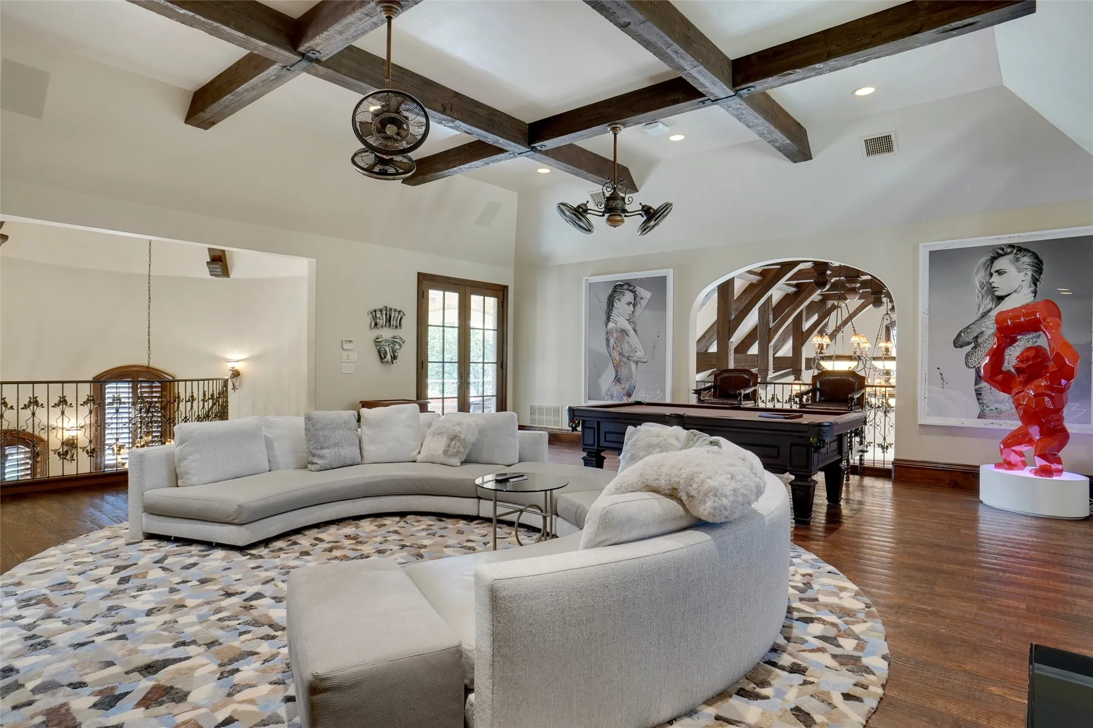 Spacious upstairs gameroom overlooking the great room in the second residence, featuring vaulted ceilings with exposed wood beams and industrial-style ceiling fans.