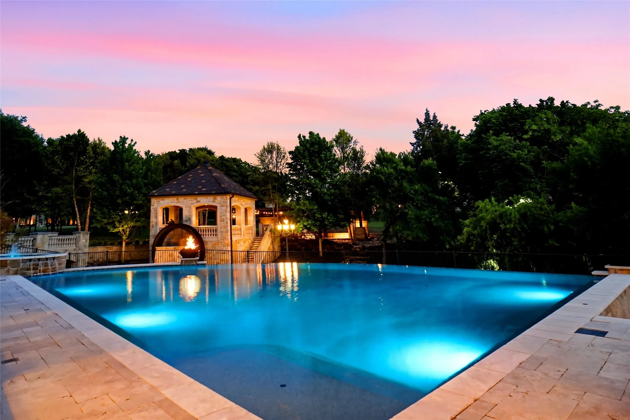 Infinity-edge pool with integrated lighting, surrounded by stone paver decking