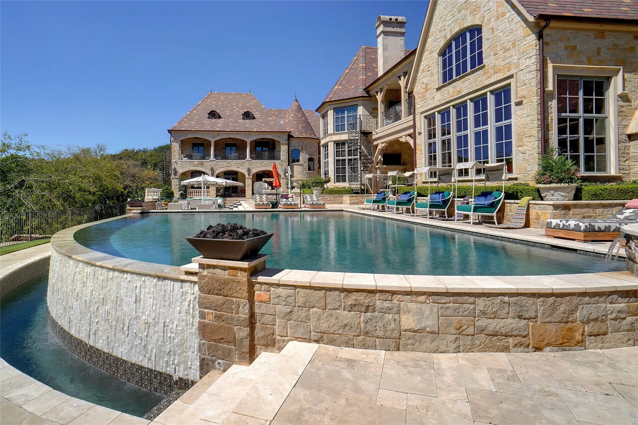 Elegant infinity-edge pool with a stone facade and spacious backyard lounge areas.