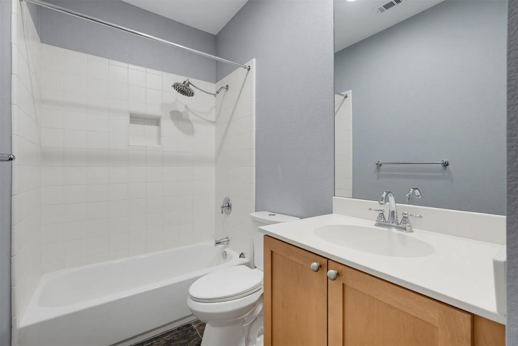 Full bathroom featuring a single vanity with wood-finish cabinetry and a light-toned countertop
