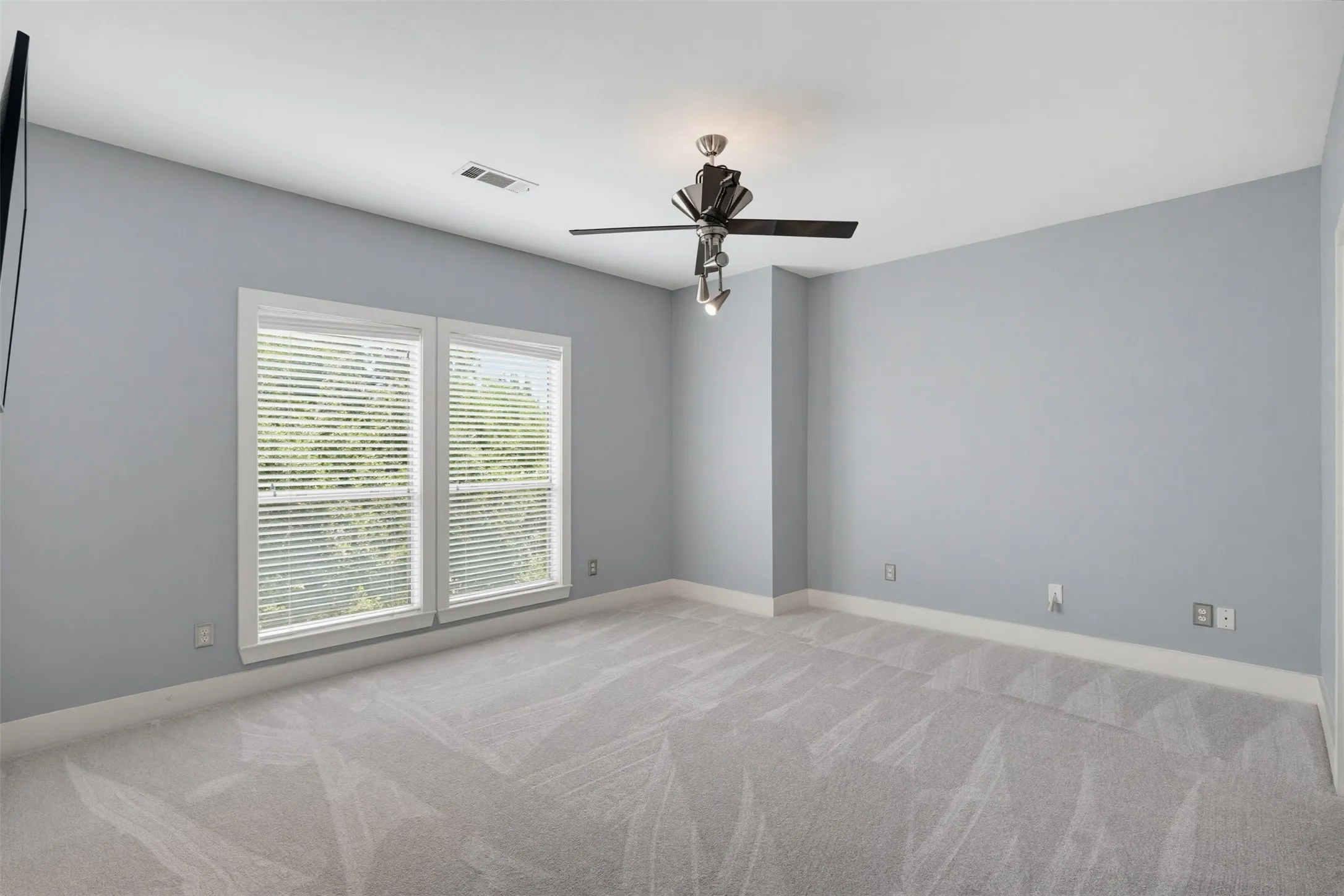 Carpeted room featuring light gray walls, white trim, and a ceiling fan with integrated lighting