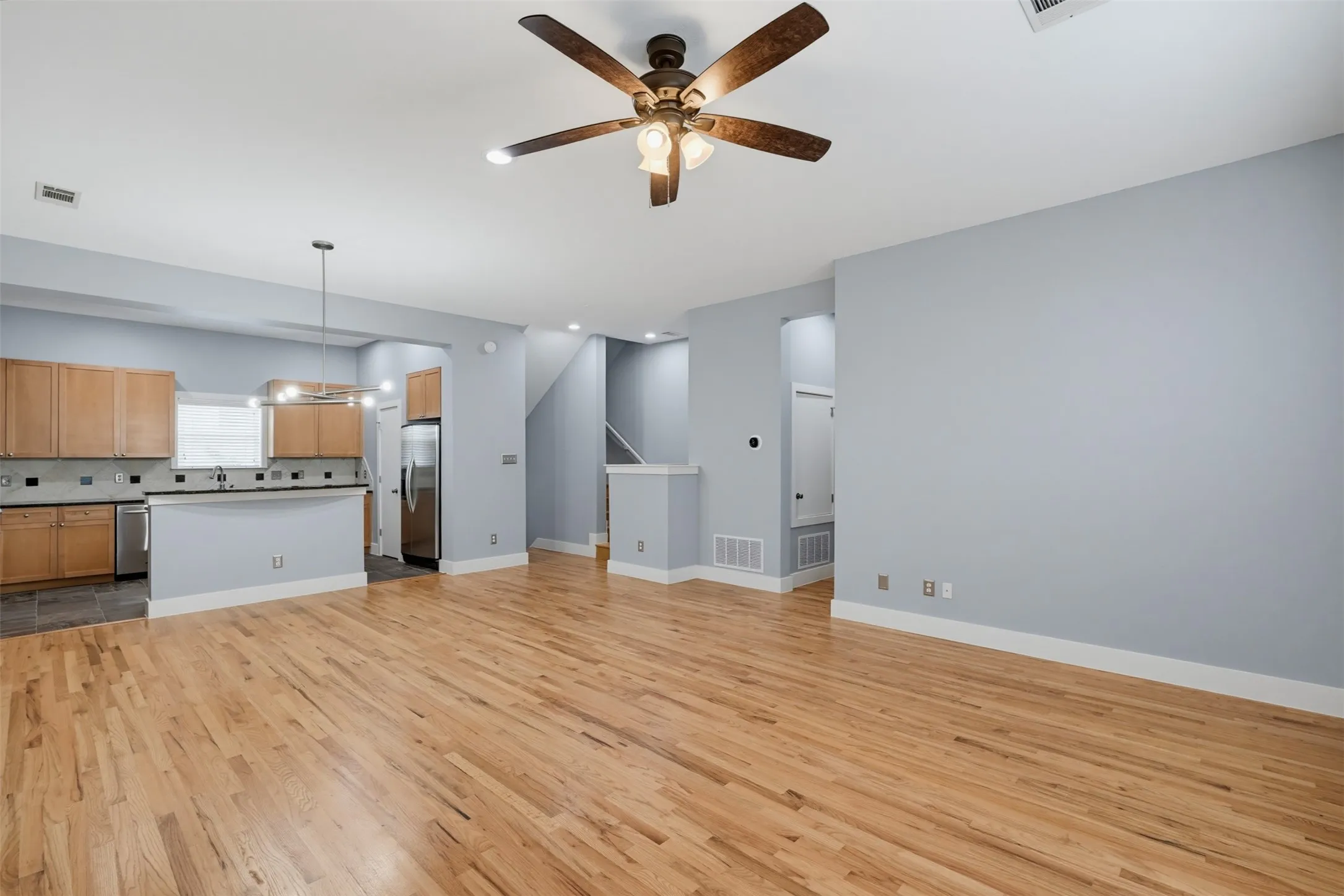 Living area featuring wood-finish flooring, a contemporary fireplace with a black stone surround and hearth, a wood mantel, recessed lighting, and a ceiling fan