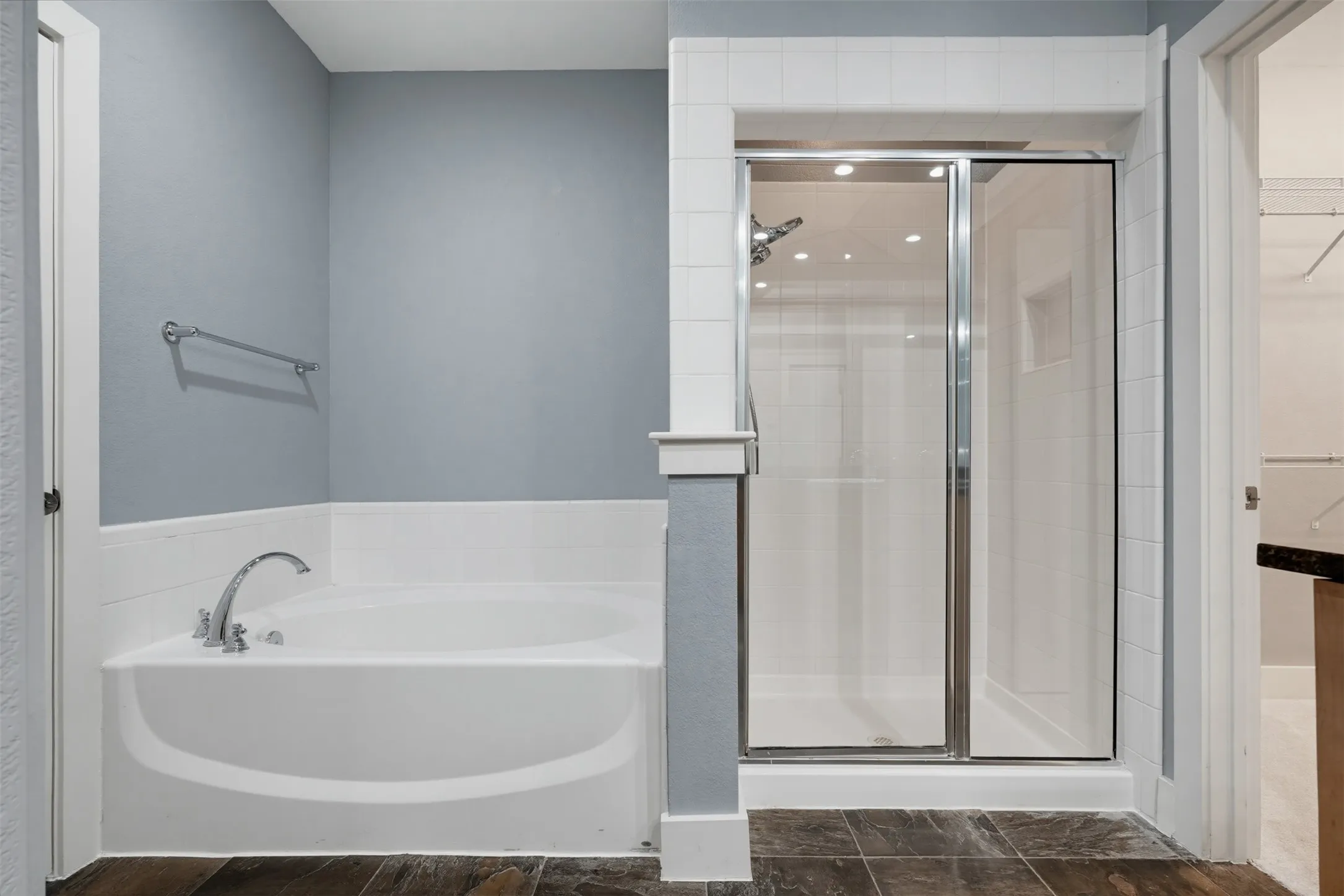 Bathroom featuring a soaking tub with chrome fixtures, a tiled shower with a glass enclosure, wood-finish flooring, and light-toned wall paint