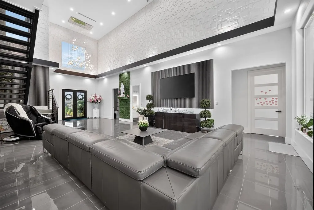 Spacious living area featuring high ceilings, large format tile flooring, and a contemporary open-riser staircase