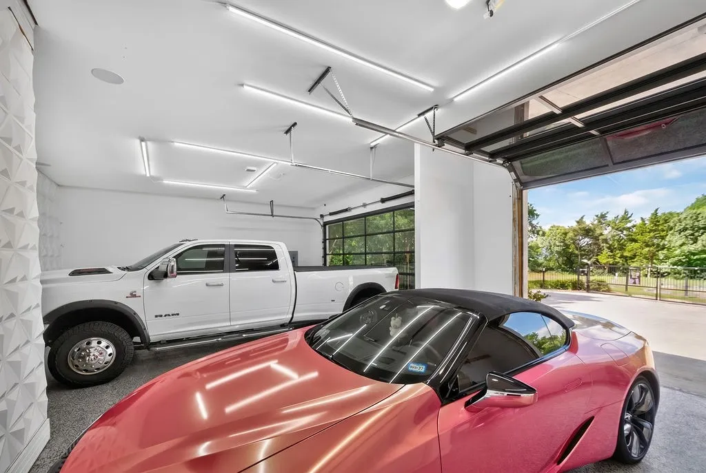 Spacious garage featuring a glass panel overhead door, high ceilings, recessed lighting, concrete flooring, and an additional overhead door visible